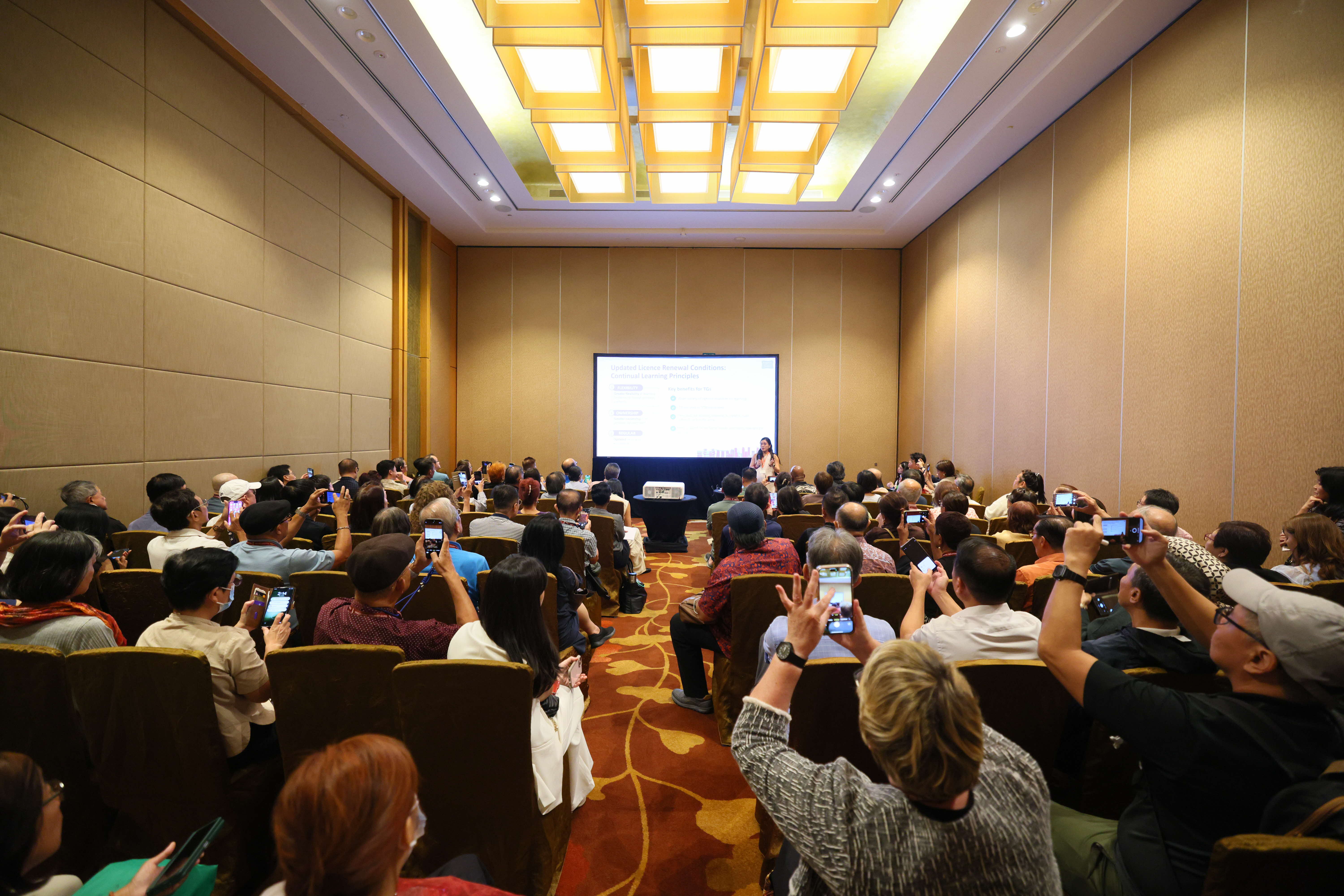 A group of tourist guide attendees taking photos & notes at breakout session on upcoming changes and licence renewal.