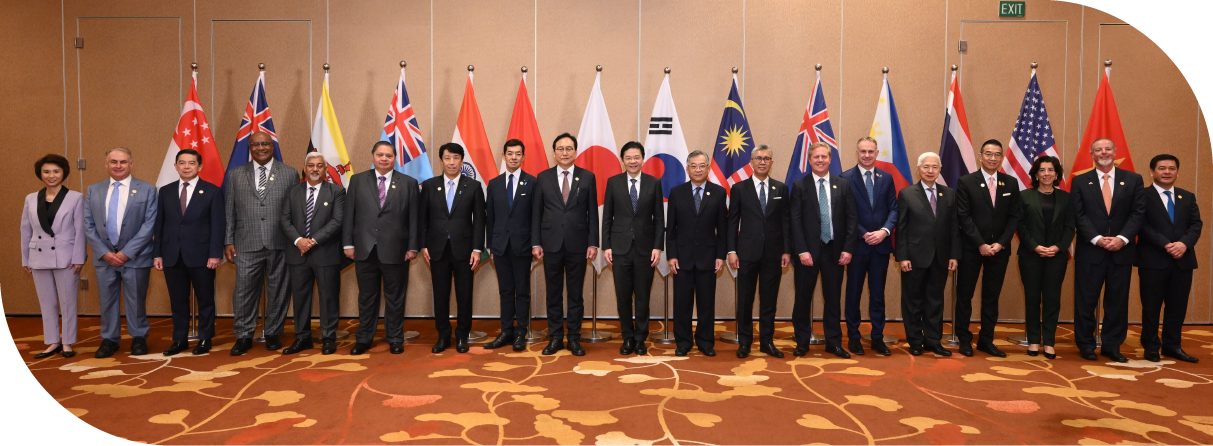 Leaders and ministers standing in one line for a photo, with flags placed behind them.