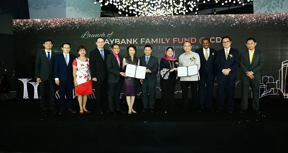 A group of people in formal attire stand together holding documents at the launch of Maybank Family Fund.