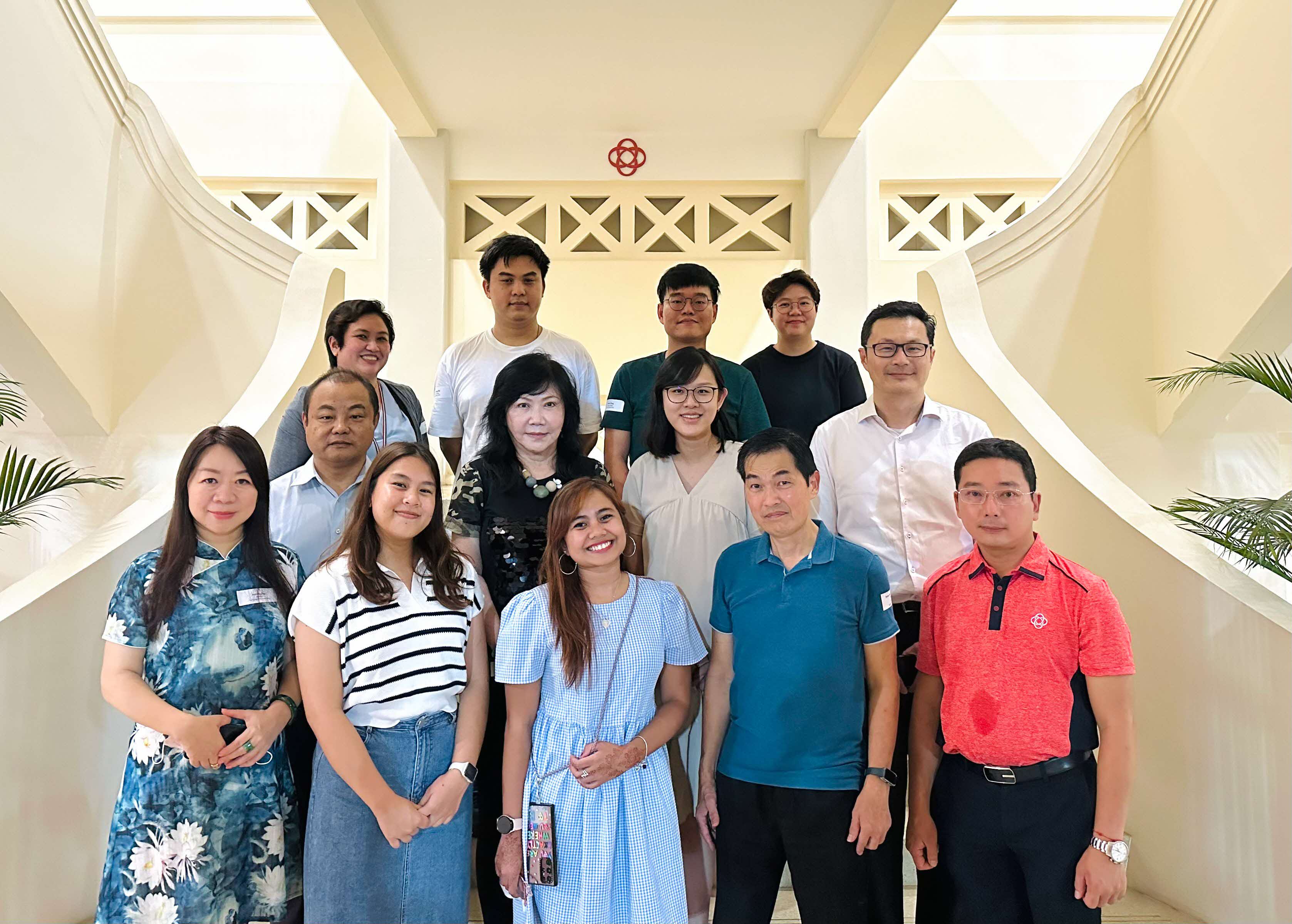 A group of people standing on stairs inside a building with white walls and decorative railings.