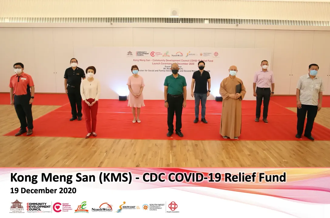 Eight people stand on a red carpet with a sign behind them reading "Kong Meng San - CDC COVID-19 Relief Fund Launch, 19 December 2020."