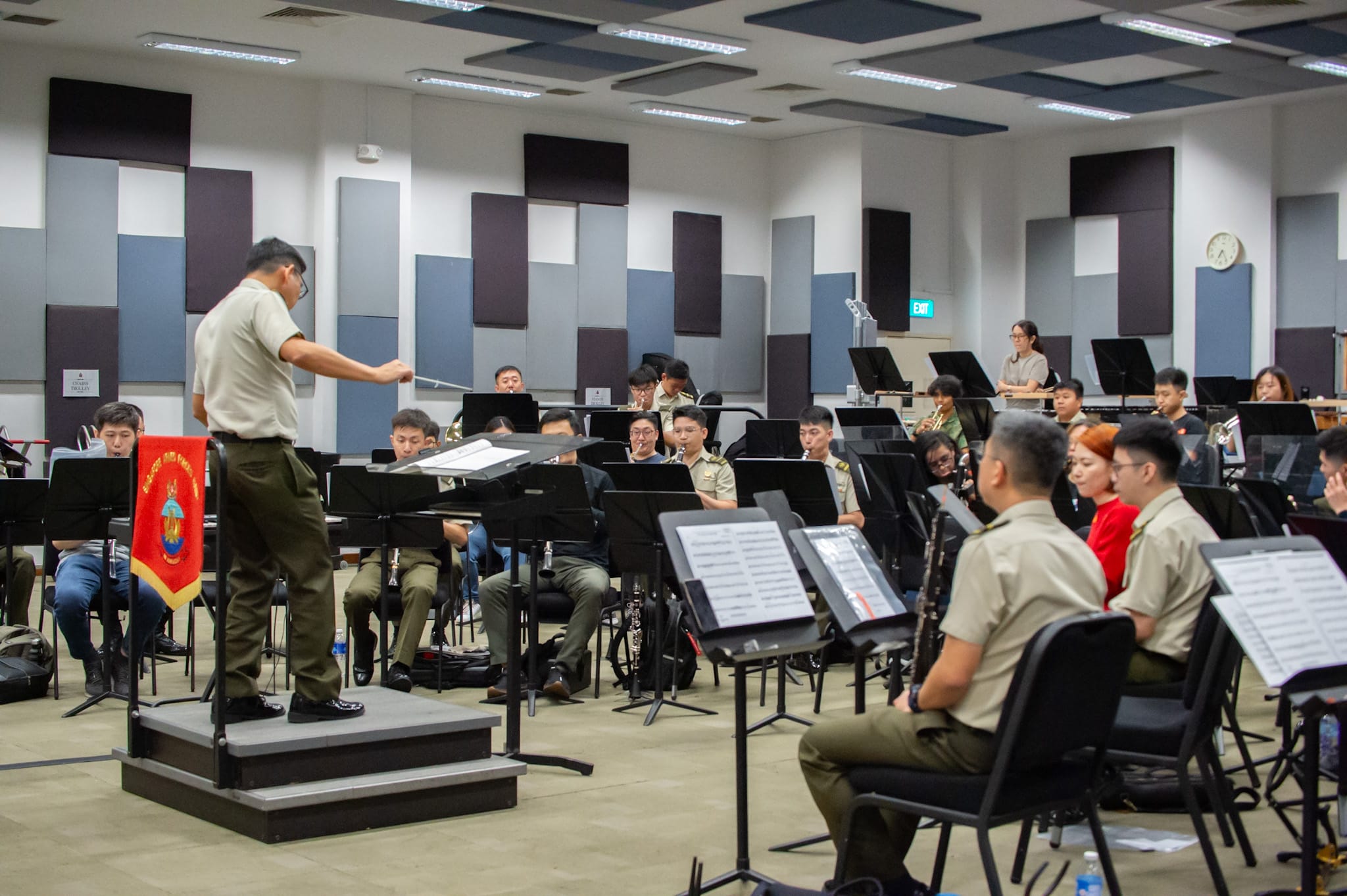 Music conductor leading a military band practice with several musicians playing instruments.