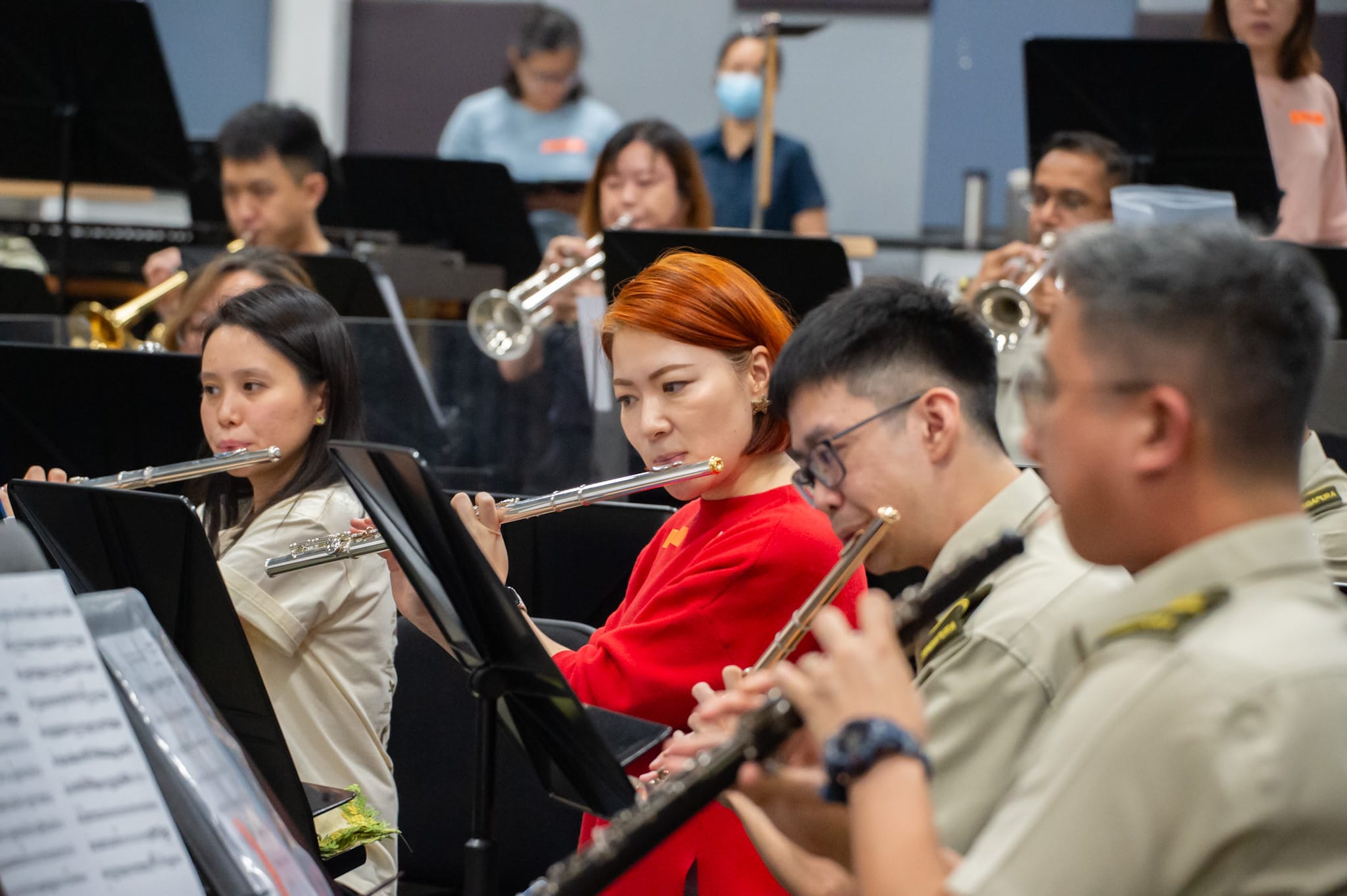 Military band members playing various instruments in a practice session.