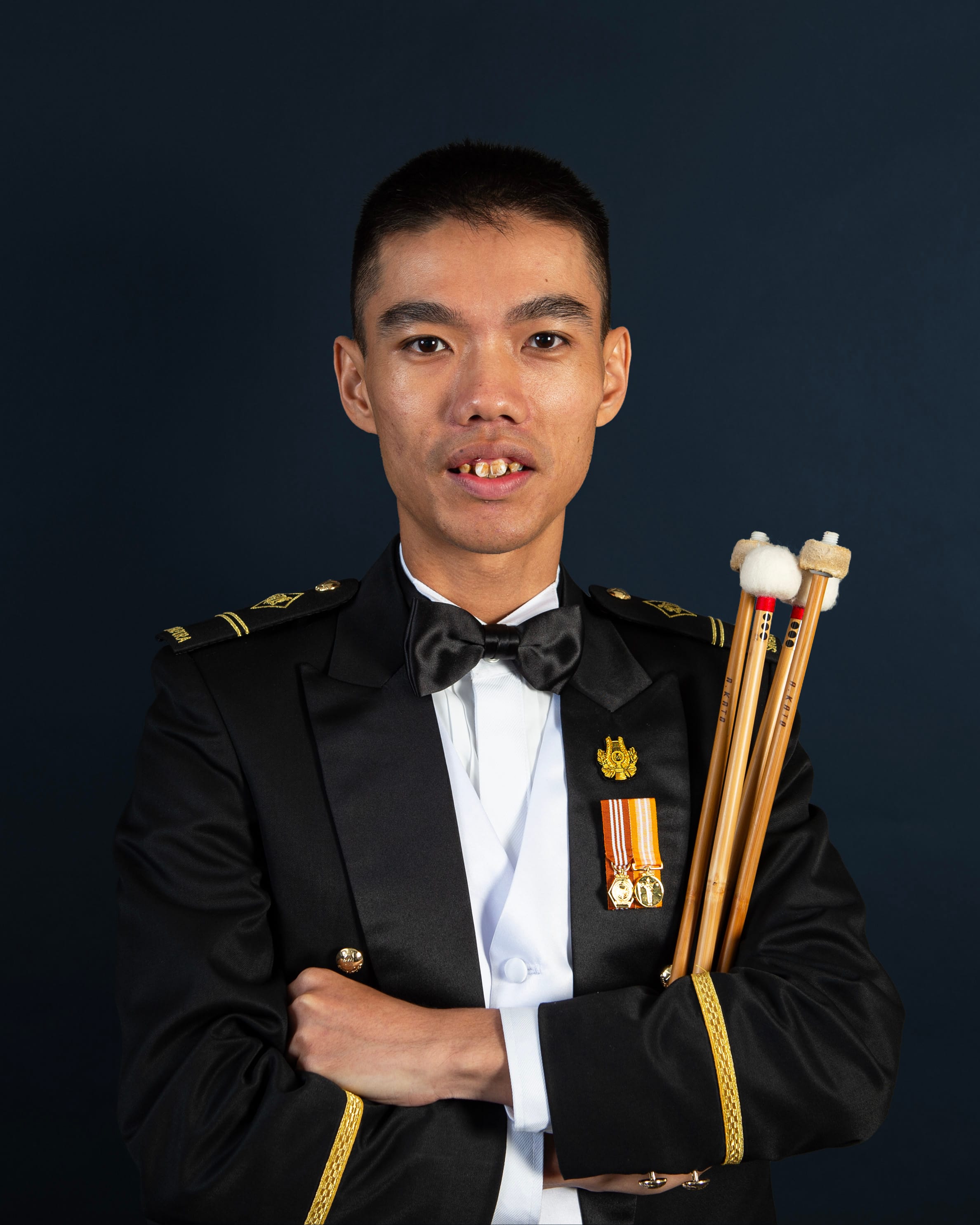 Portrait of ME2 Lim Xing Hong in uniform with a percussion sticks.