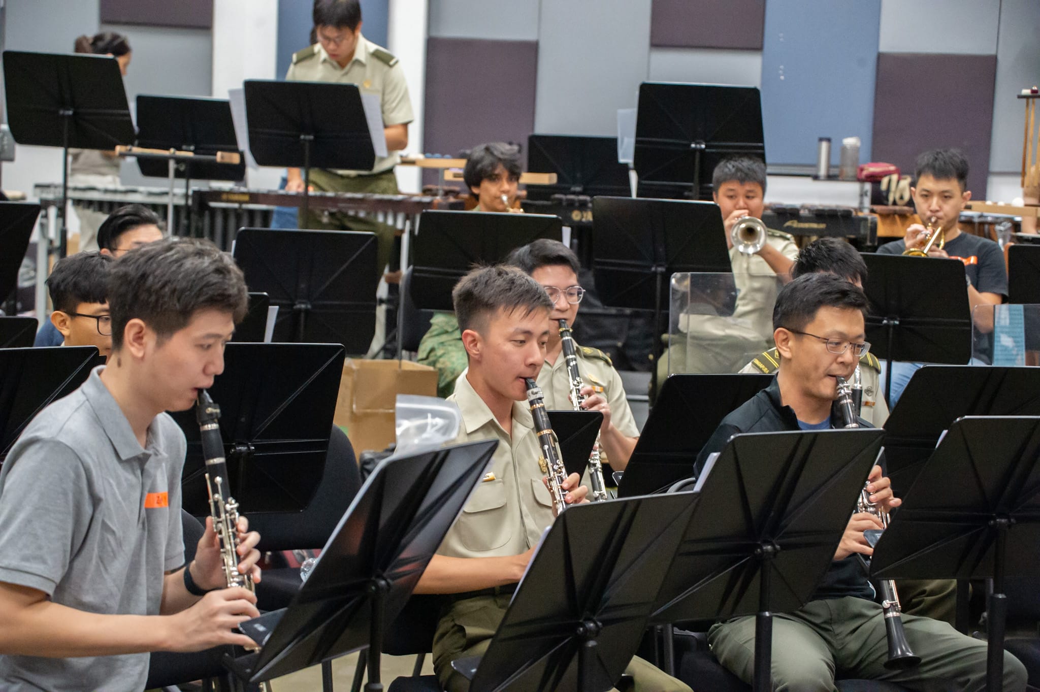 Musicians playing clarinets and trumpets in a military band practice session.