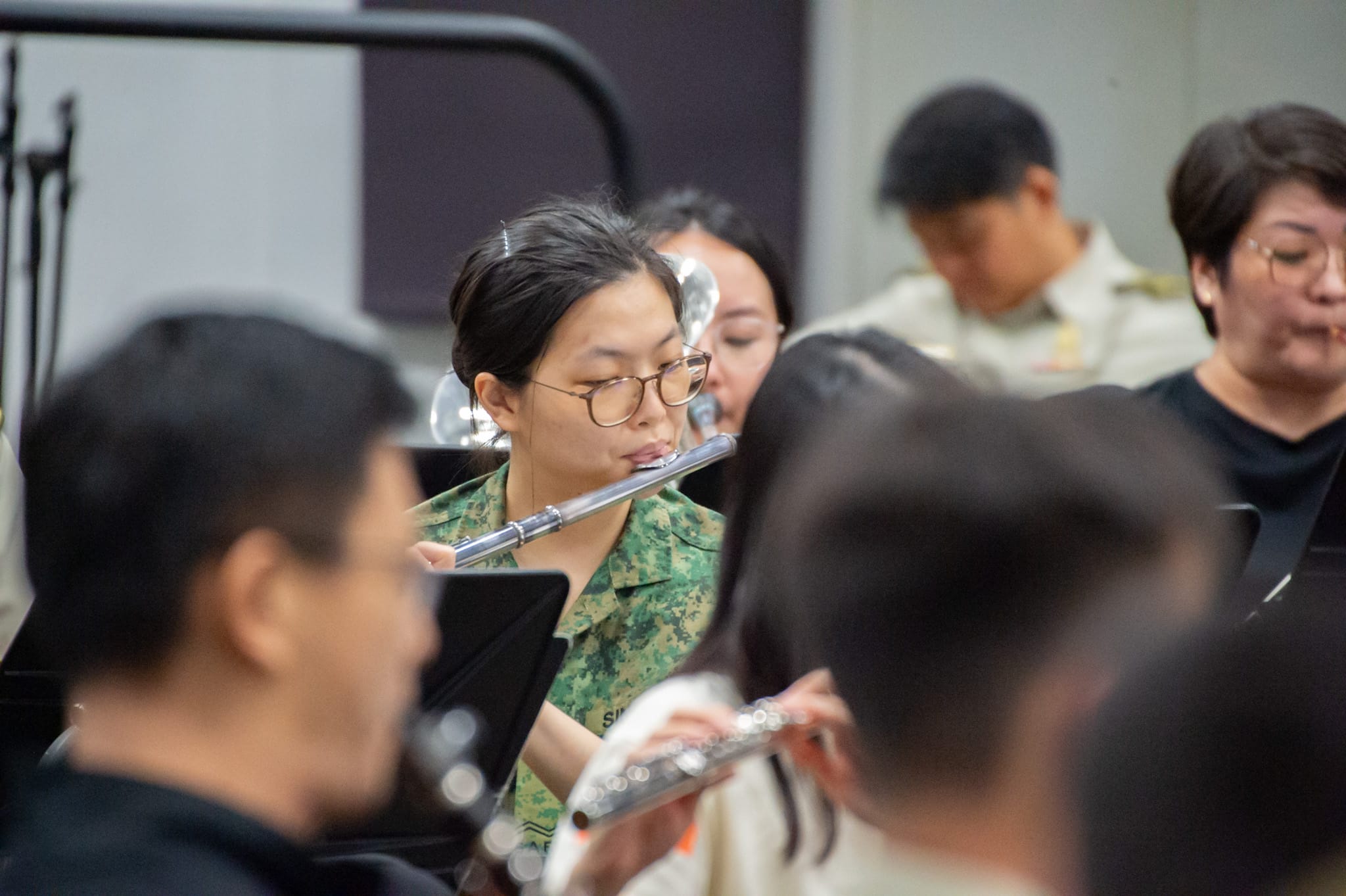 Flute players in a military band playing during practice with sheet music in front.