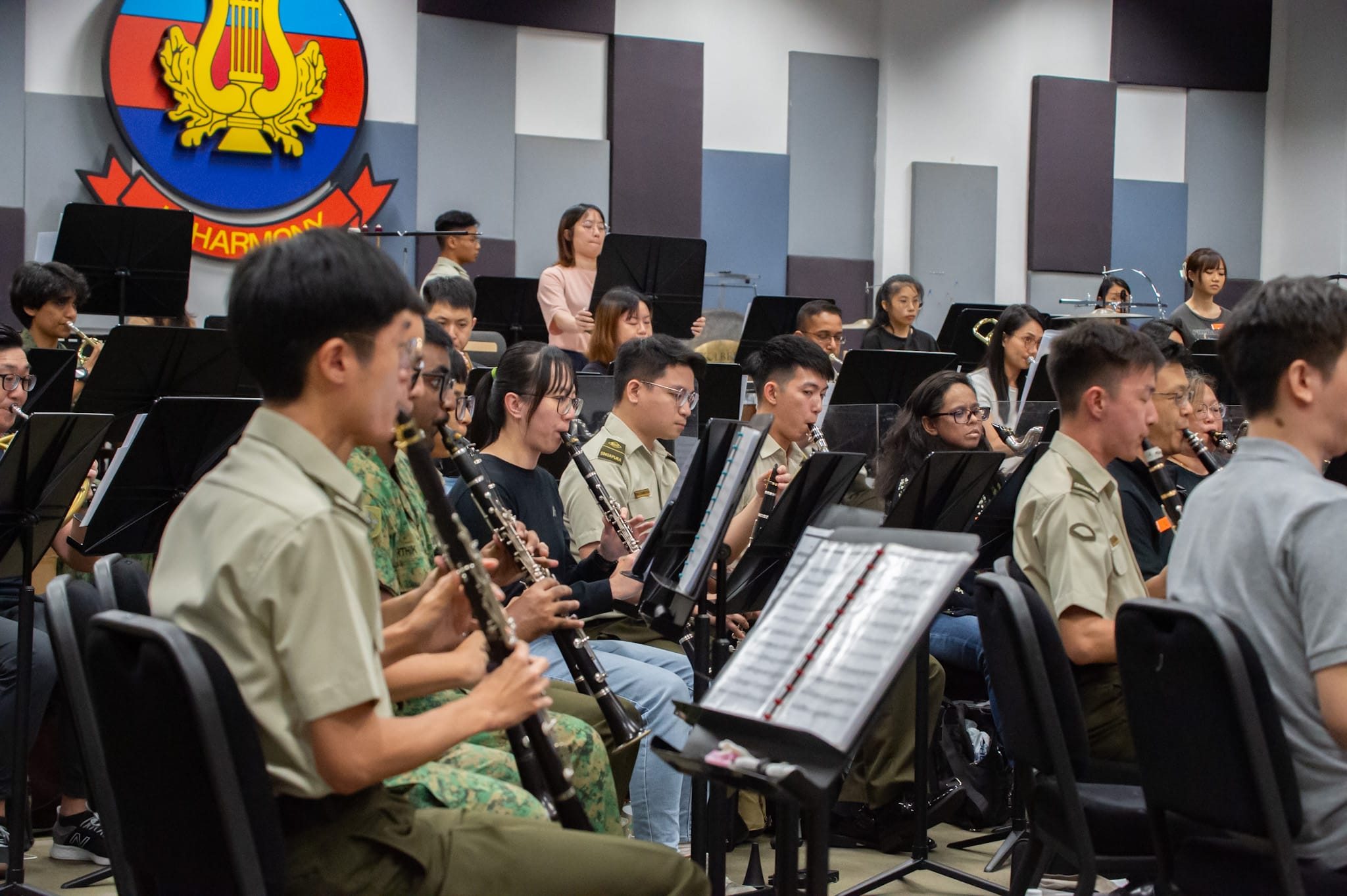 Musicians playing woodwind instruments in a military band rehearsal.