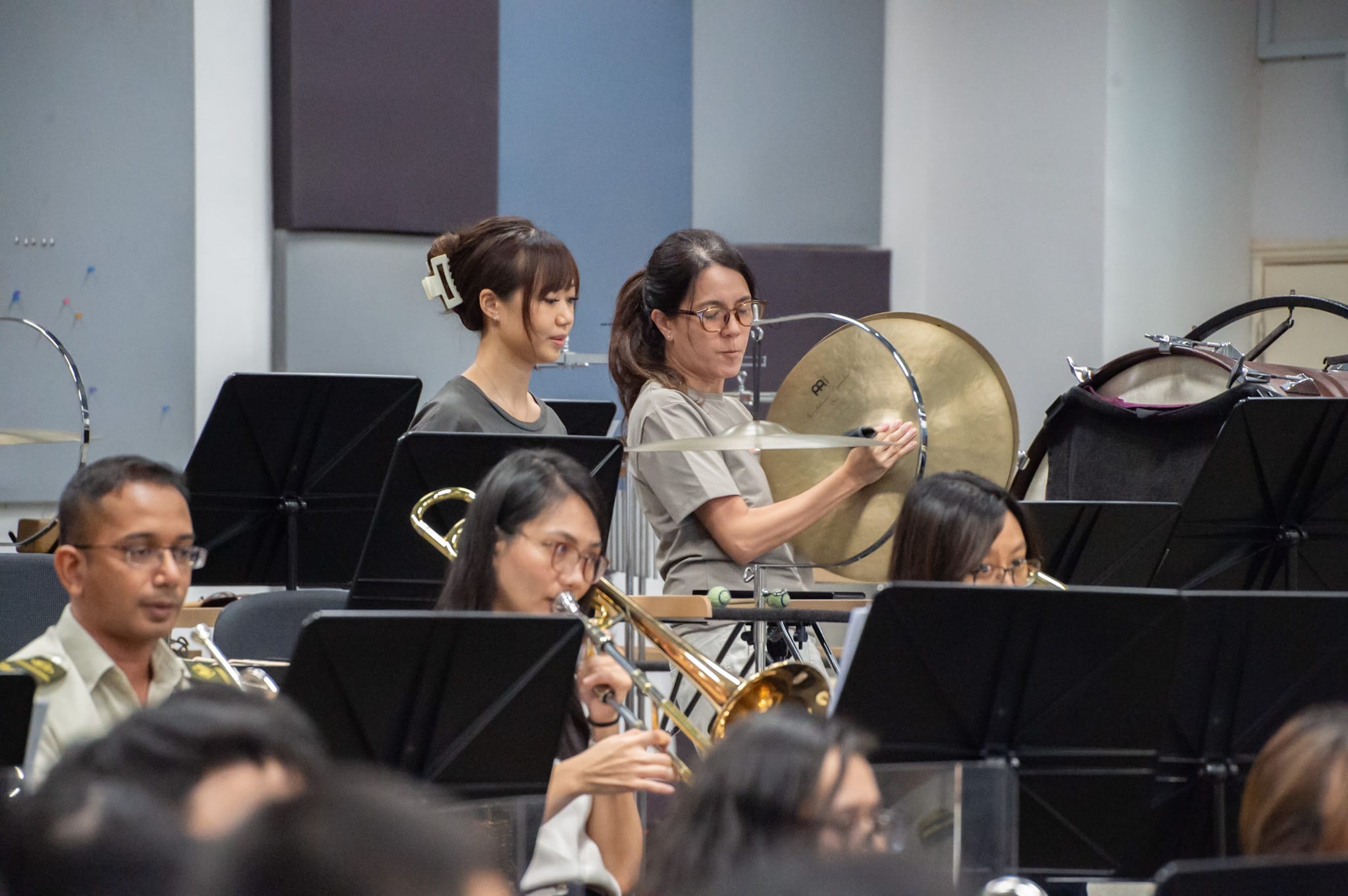 Percussionists playing cymbals and other instruments during a military band rehearsal.