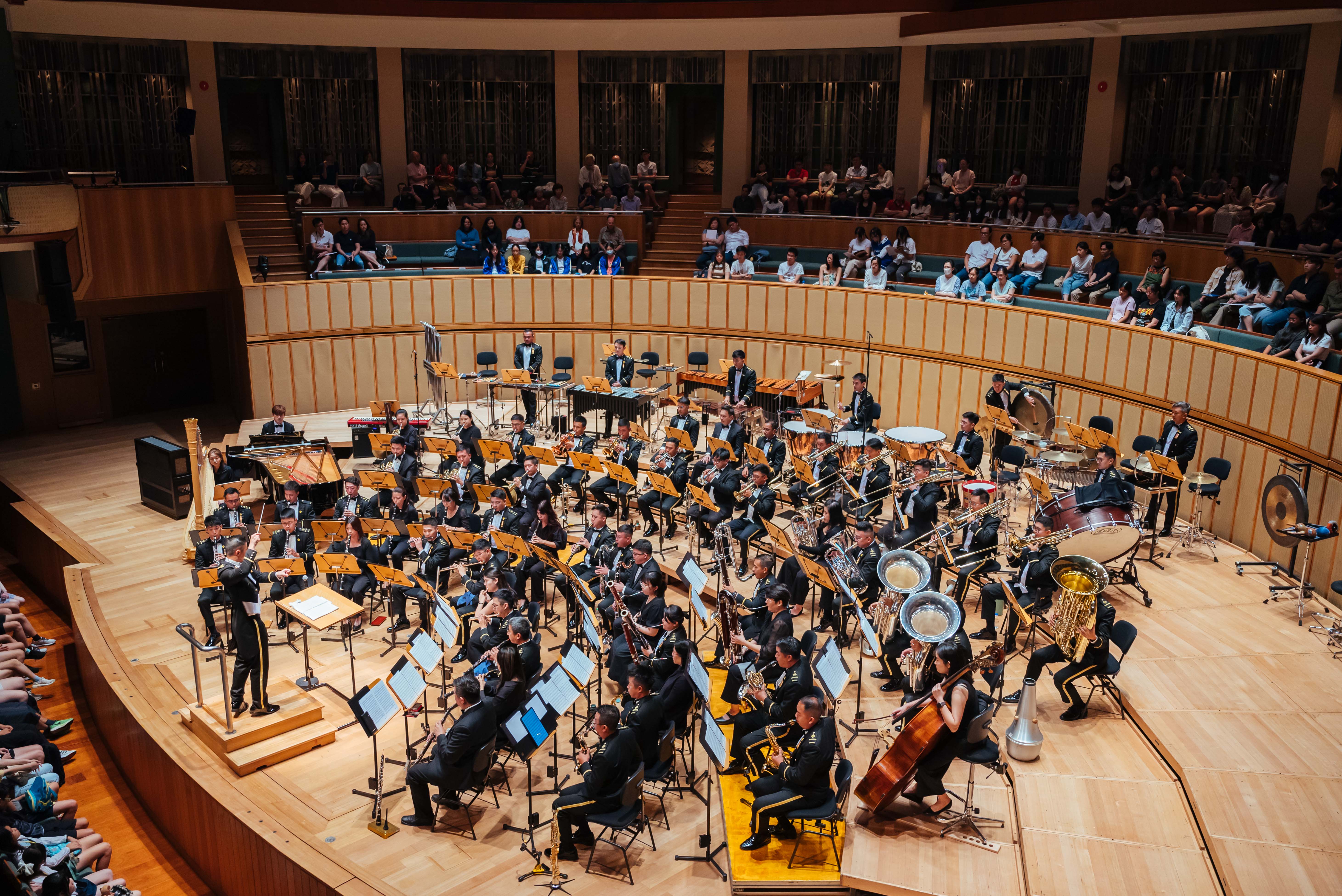 SAF Band in formal black attire performing symphonic concert in a grand concert hall 