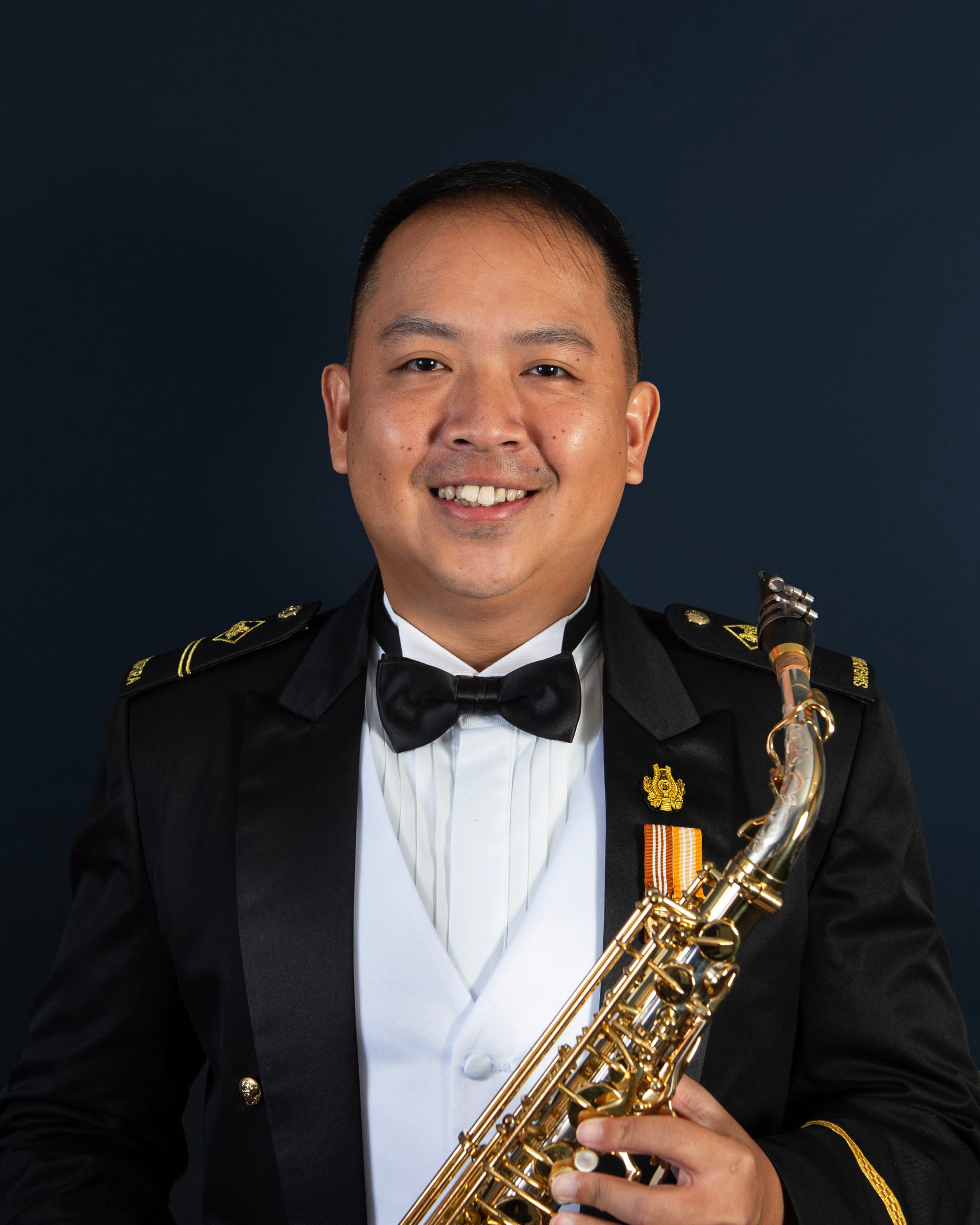 Portrait of ME2 Pee Jun Ming in uniform with a saxophone.