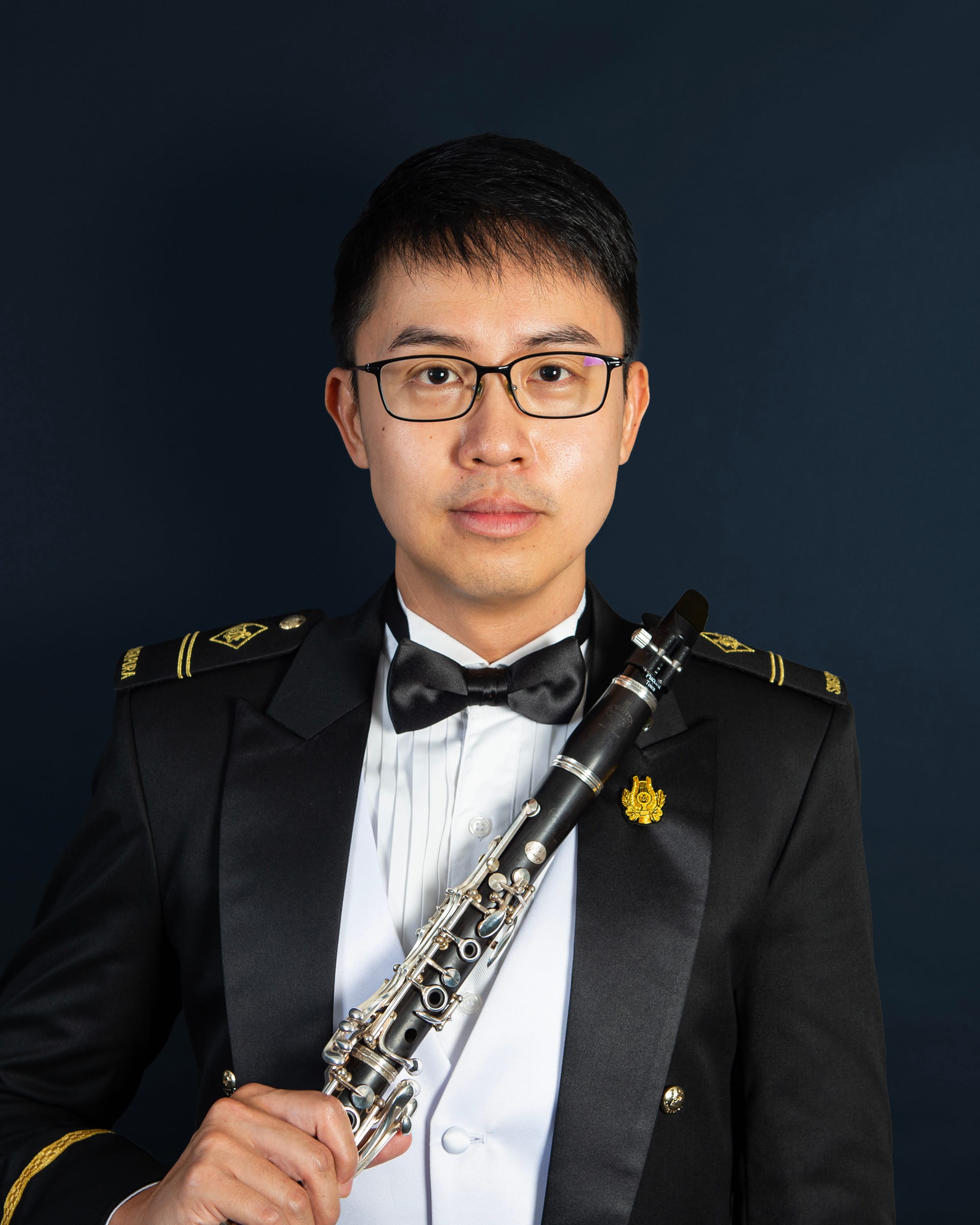 Portrait of ME2 Benjamin Wong in uniform with a clarinet.