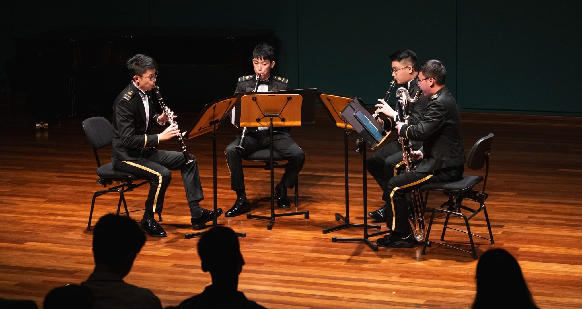 SAF clarinet quartet performs on stage for an audience in a chamber music setting.