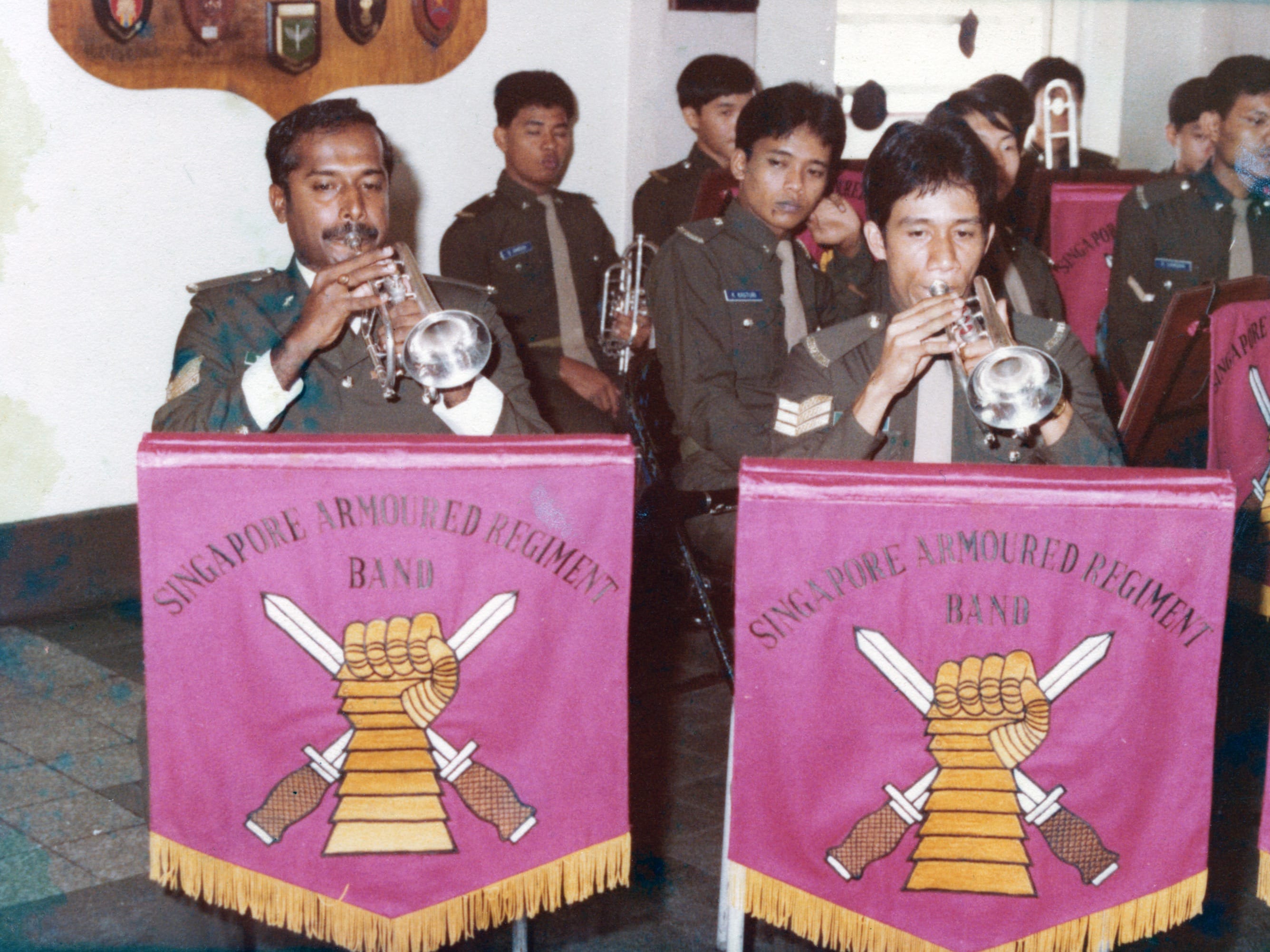 Singapore Armoured Regiment Band members playing trumpets in a rehearsal room.
