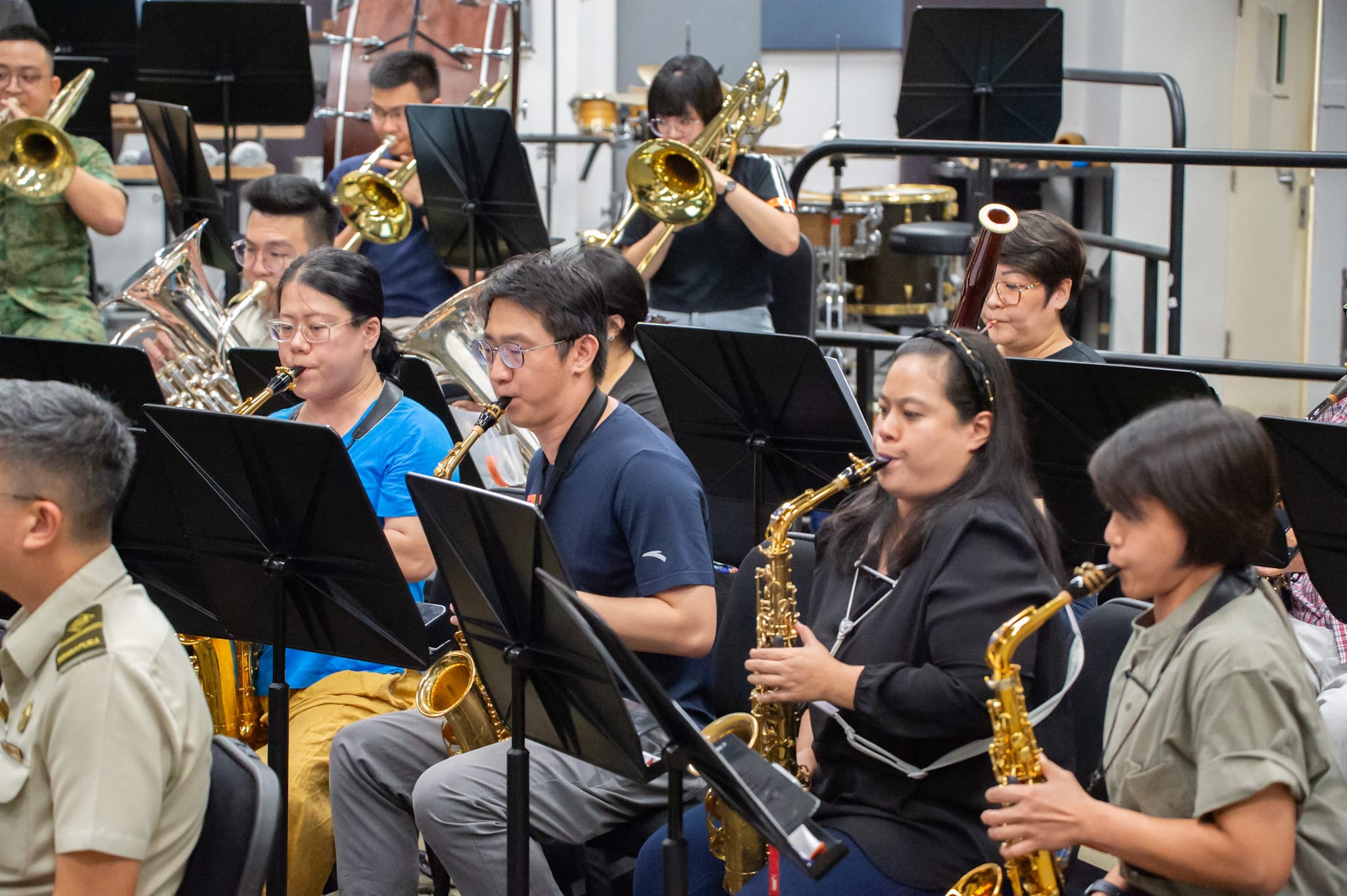 Musicians playing saxophones and brass instruments during a military band practice.