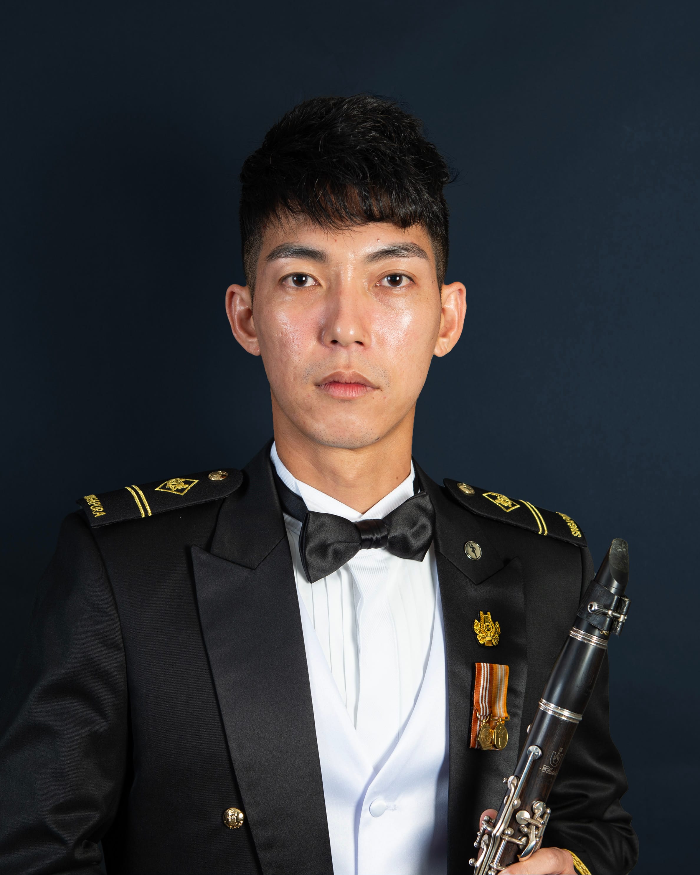 Portrait of ME2 Tan Yue Yuan in uniform with a clarinet.