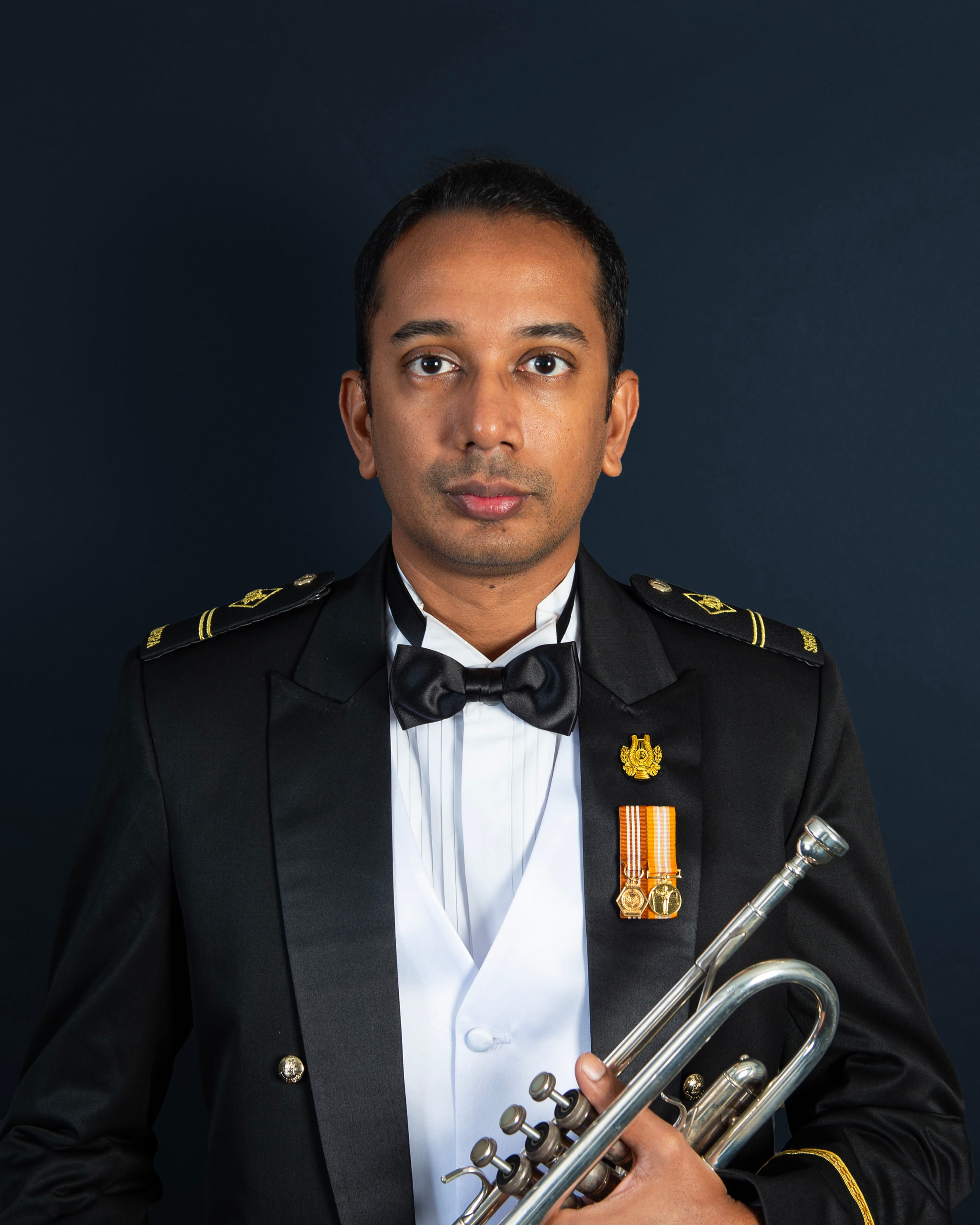 Portrait of ME2 Vignesh in uniform with a trumpet.