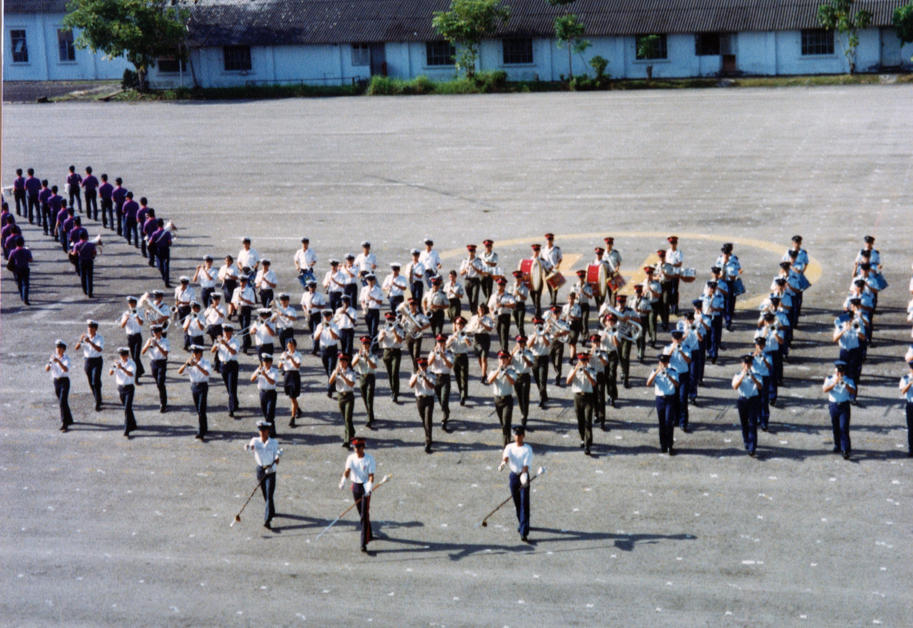 SAF Band performing in formation with service-specific groups during a parade drill.