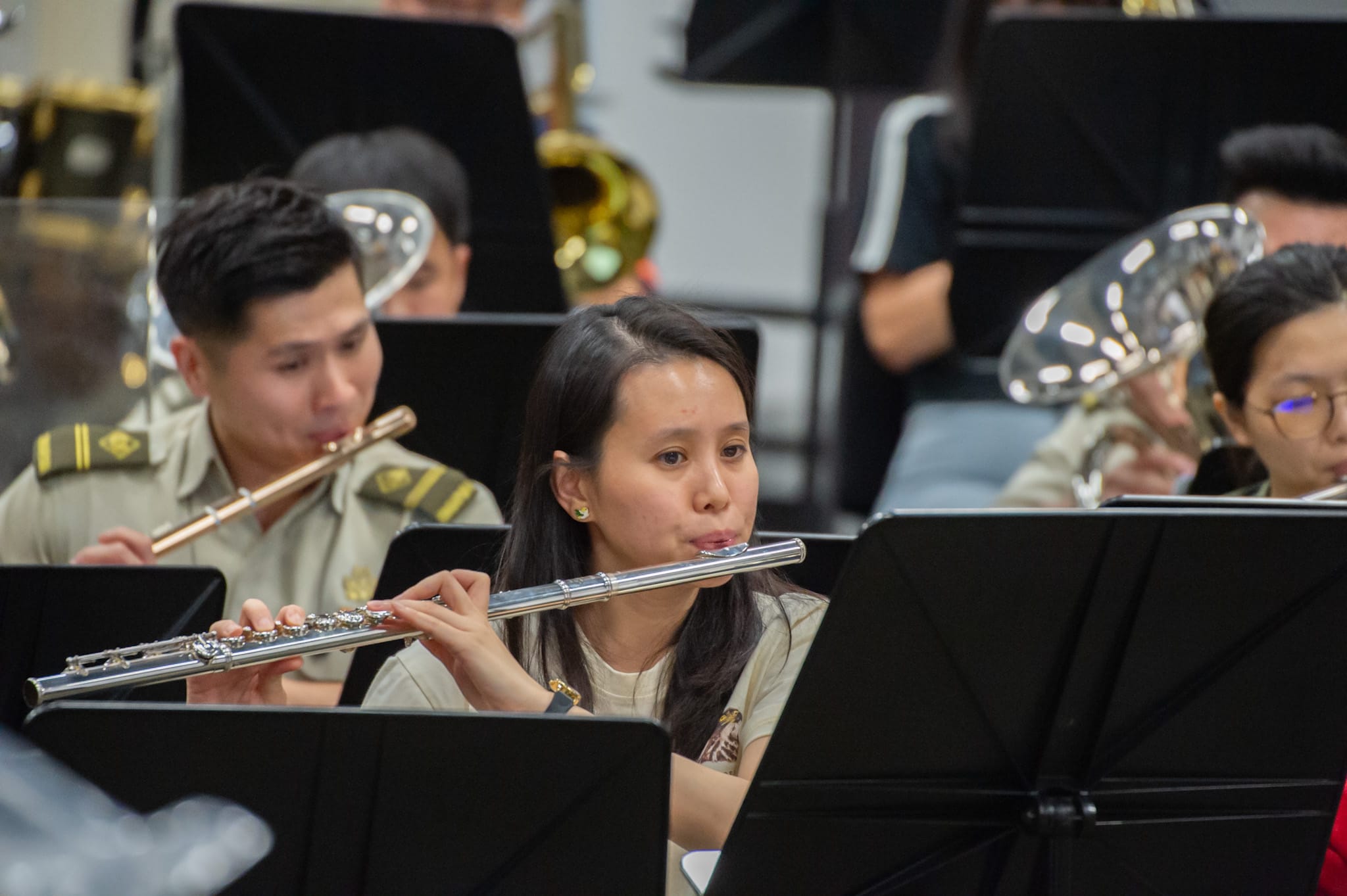 Close-up of a musician playing a flute in a military band during practice.