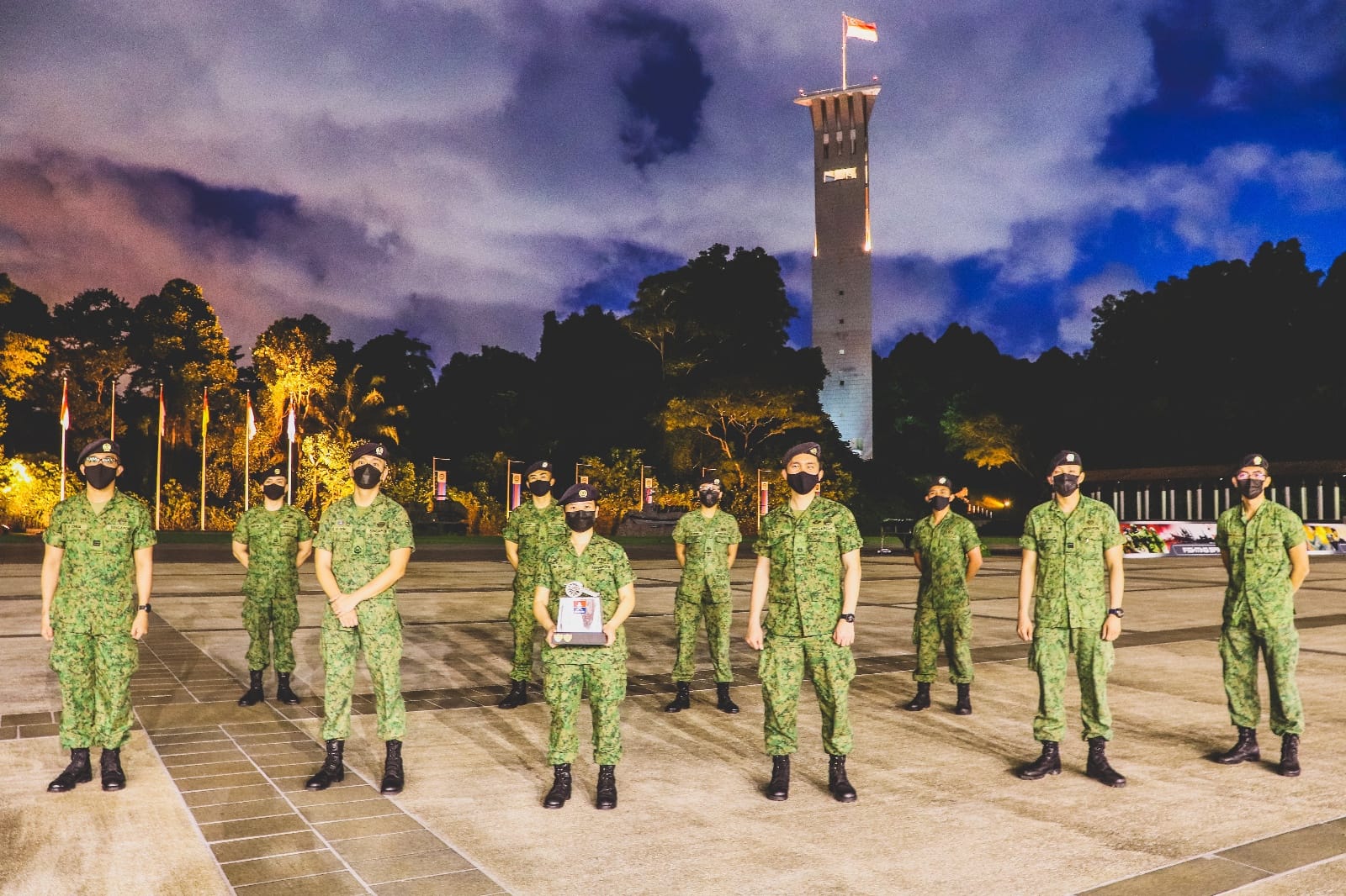 LTC Lim En with soldiers at dusk in front of the SAF memorial tower.