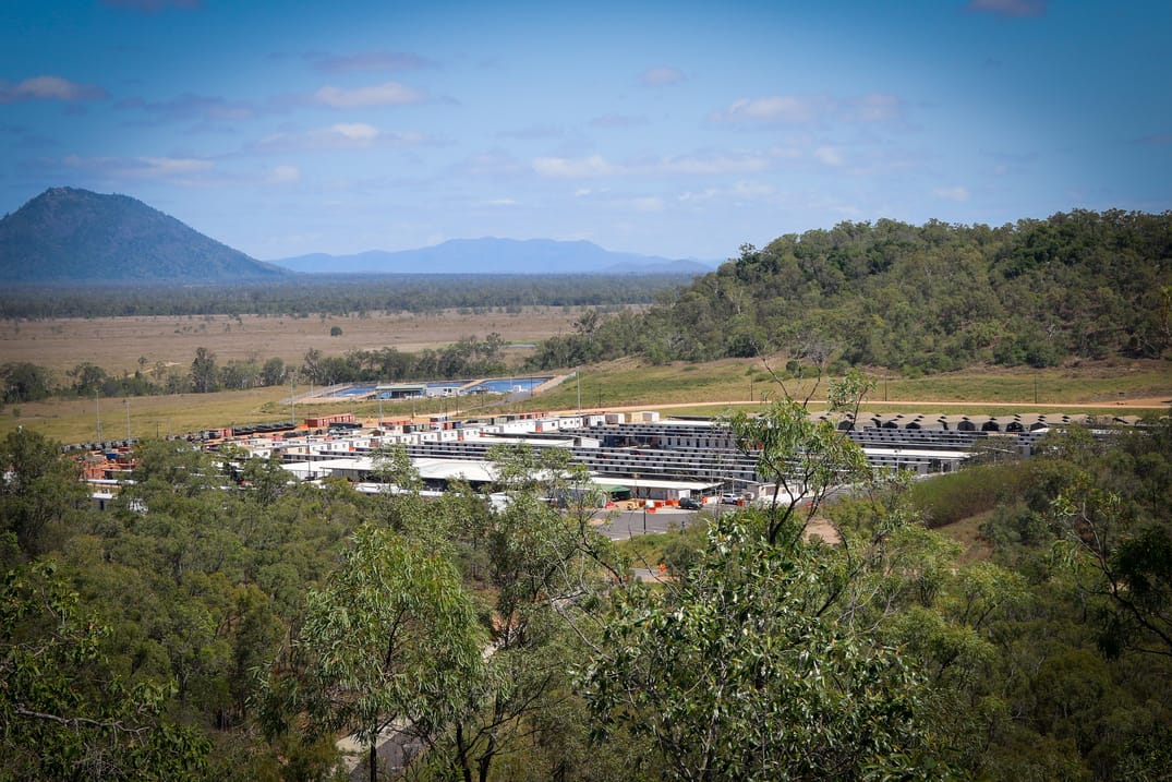 Aerial view of military training camp set in a forested valley.