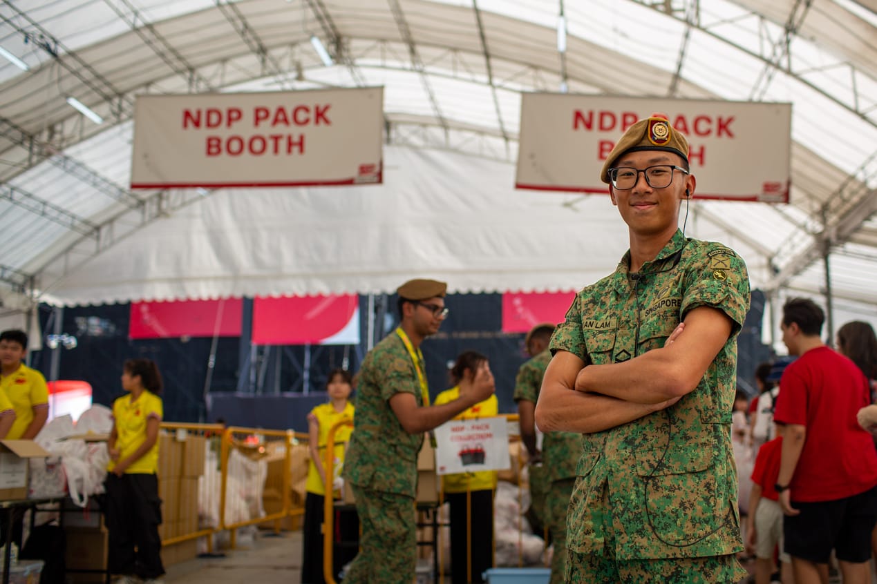 SAF soldier posing in front of NDP pack booth at the event venue.