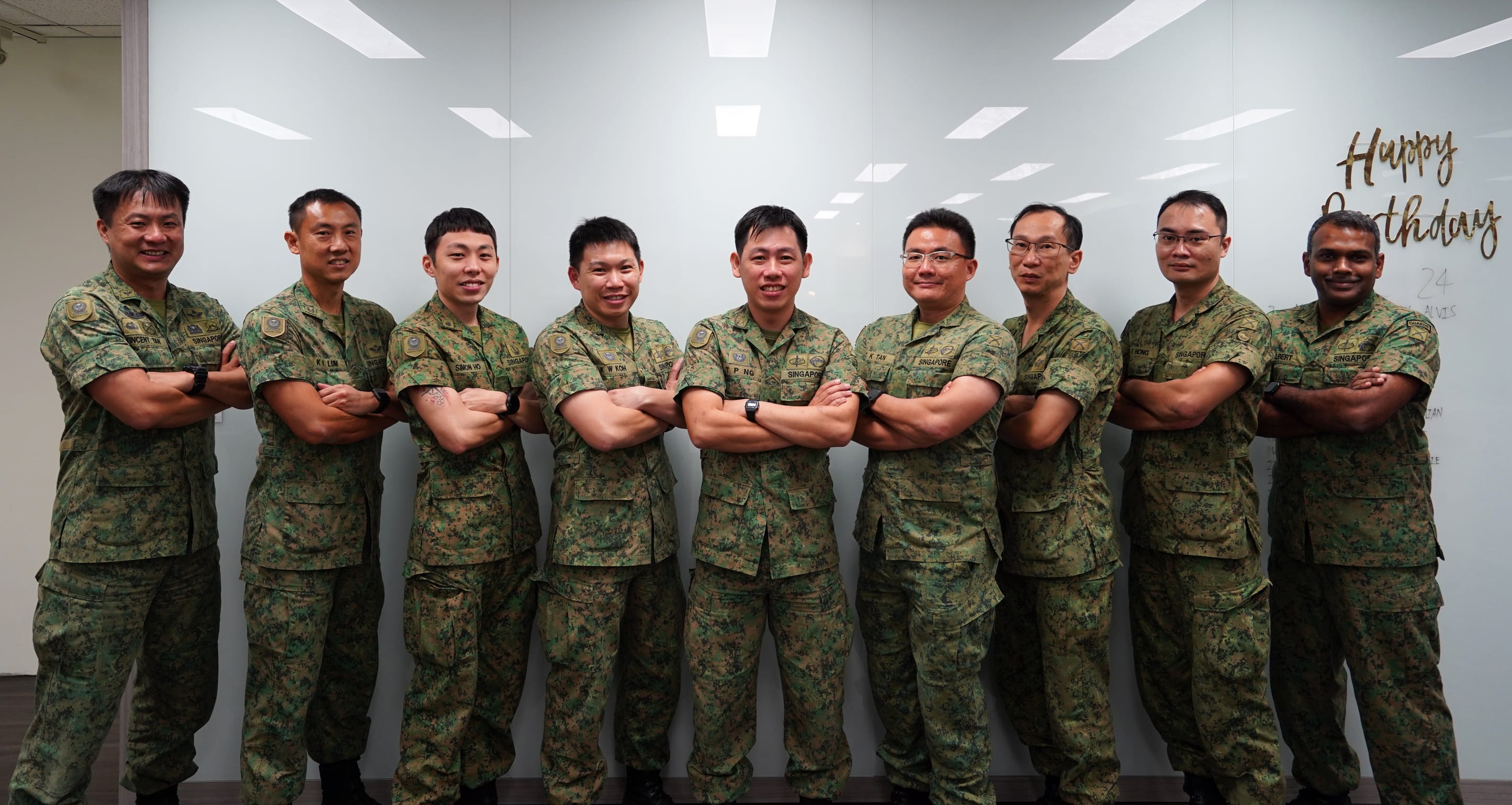 LTC Ng Tze Peng standing with colleagues in uniform, arms crossed and smiling.