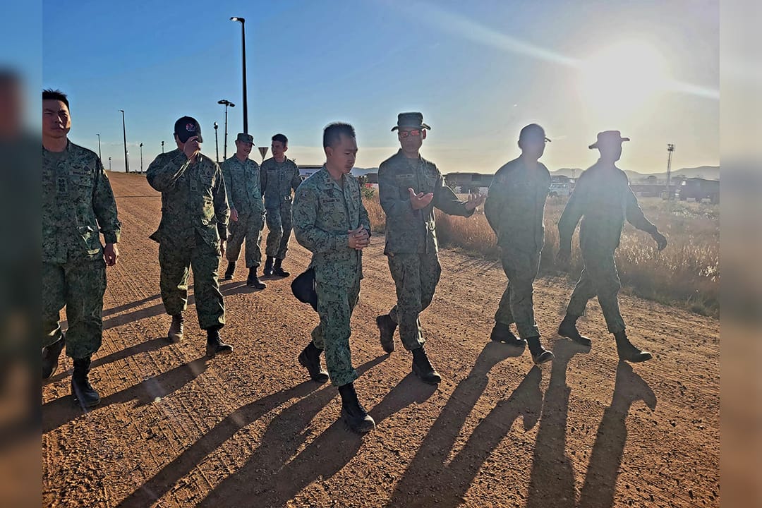 Soldiers walking and conversing on a dirt path during field training.