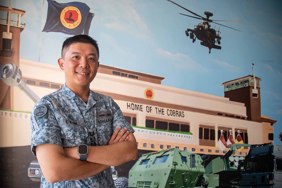 COL Oh Chun Keong with arms crossed in front of an army mural.
