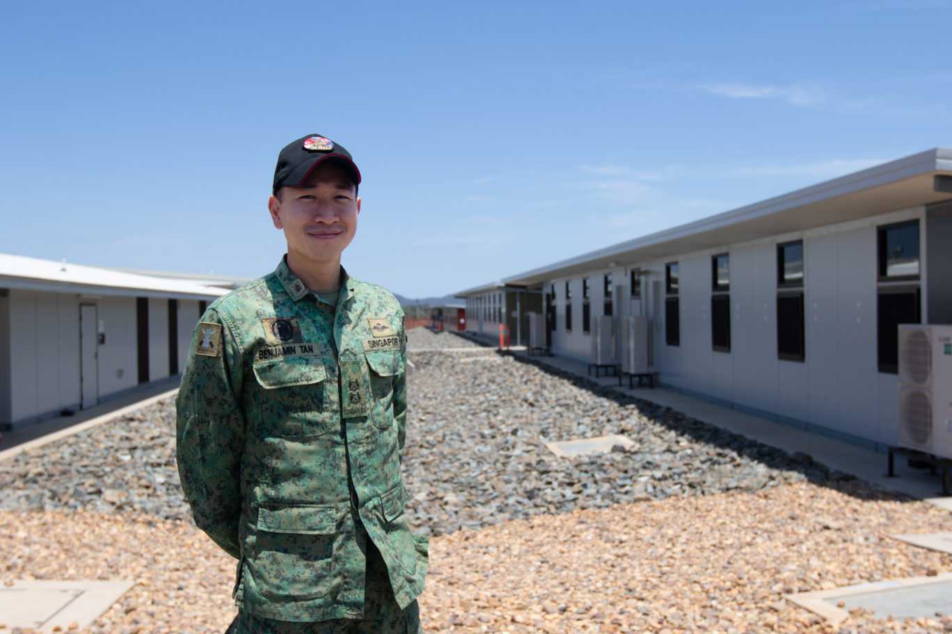LTC Benjamin Tan smiling outdoors in uniform at a training facility.