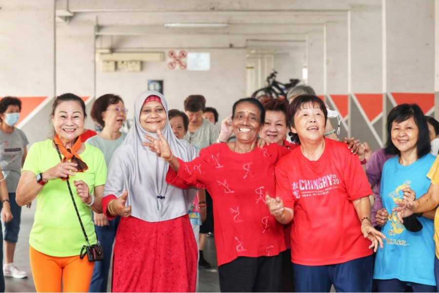 Group of elderly women smiling and dancing, promoting community wellness.