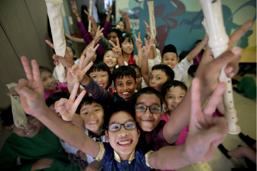 A group of children in colorful clothing, smiling and posing with musical instruments.