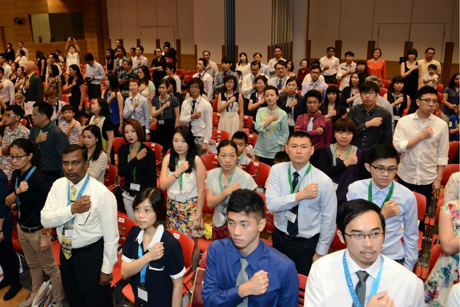 Group of individuals standing with hands over their hearts, participating in a pledge.