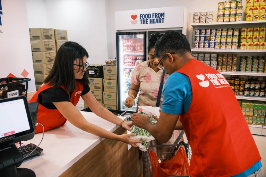Volunteers assisting customers with grocery items at a food distribution center.
