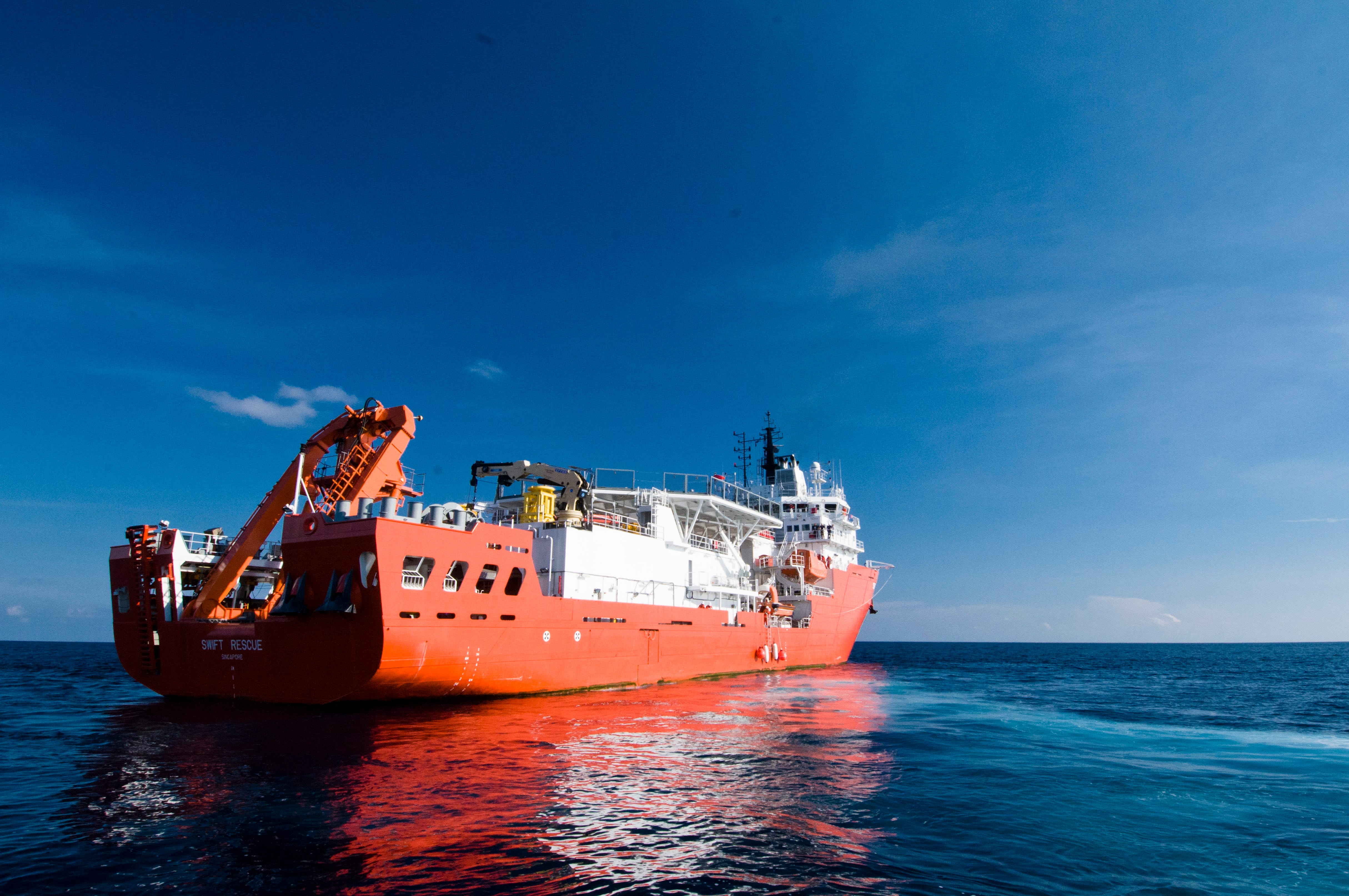 Bright orange rescue vessel “Swift Rescue” is docked in open waters under a clear blue sky.
