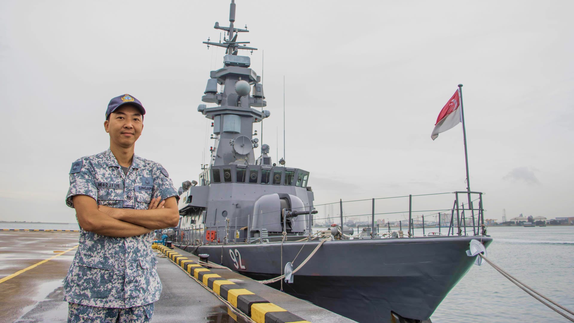 ME4 Lye stands proudly on a wet dock beside a patrol vessel flying the Singapore flag.