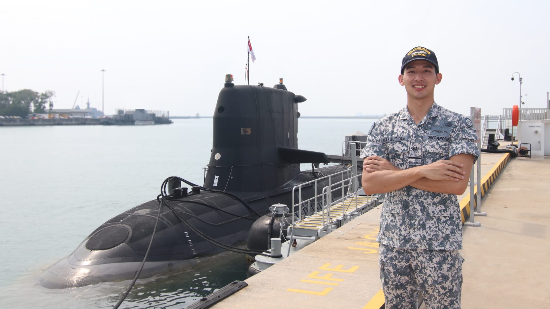 ME4 Lloyd in uniform smiling beside docked submarine in calm waters
