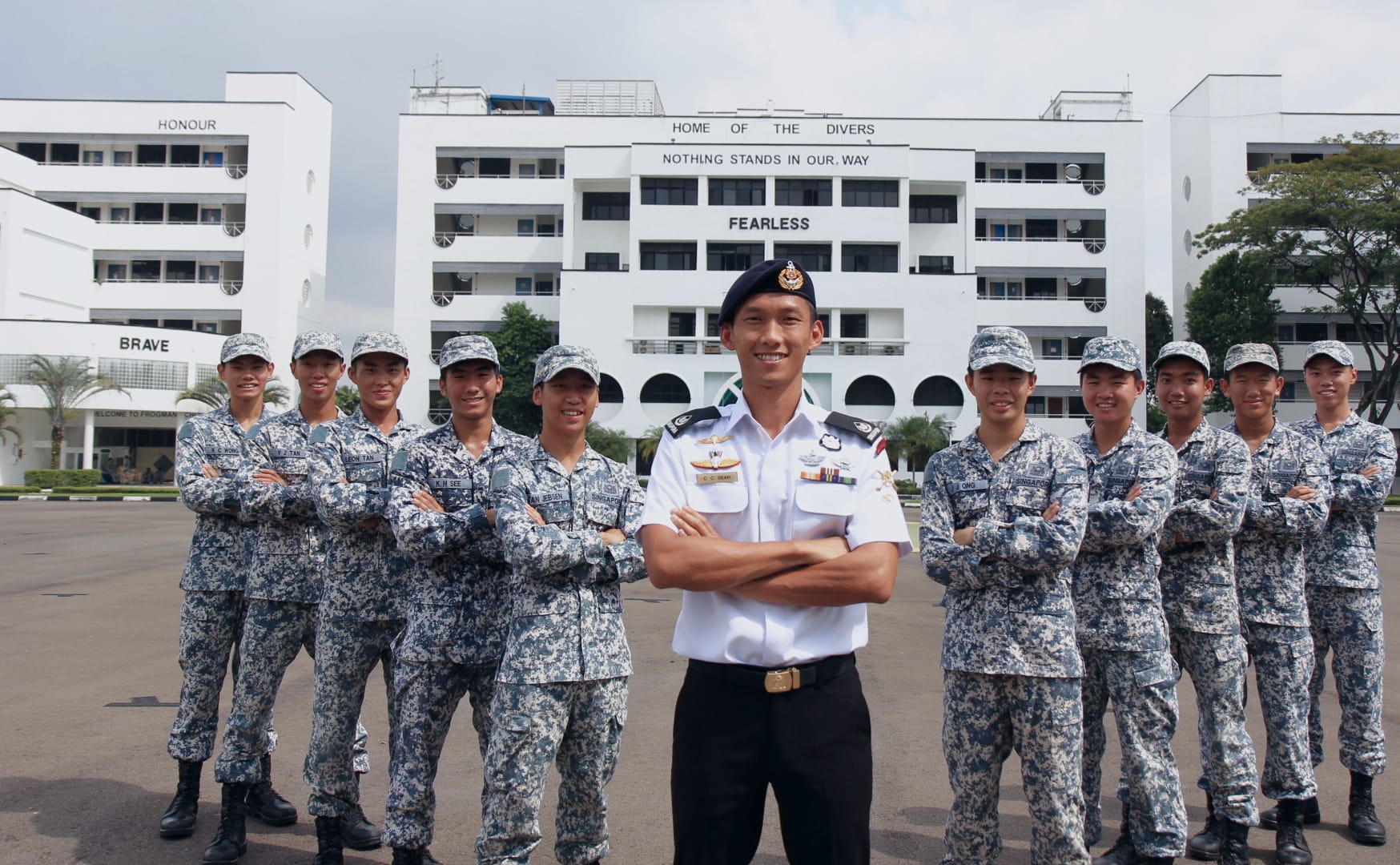 1WO Hans Seah with Navy divers poses in front of SAF diving school building marked “FEARLESS.”