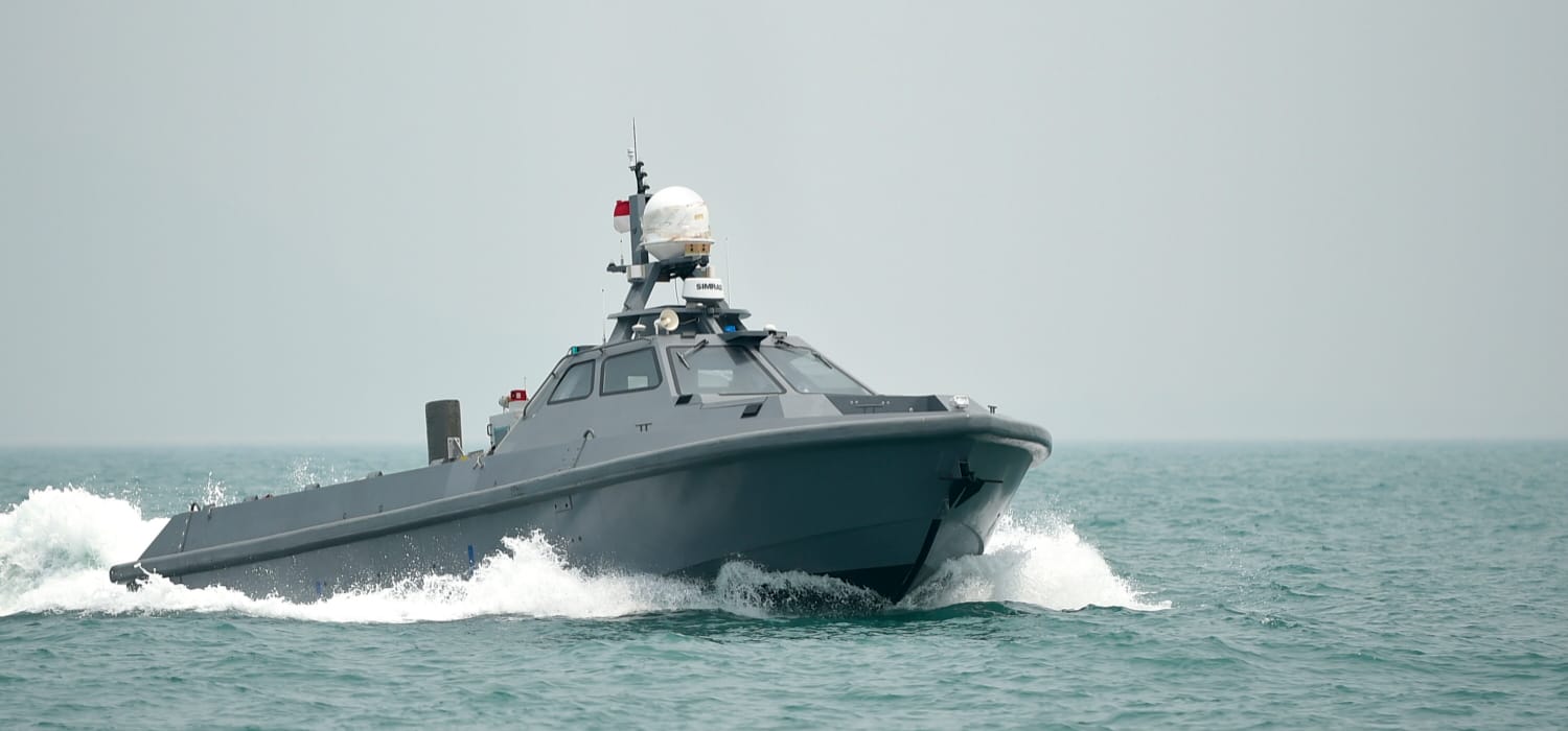 Grey unmanned surface vessel cruising at speed