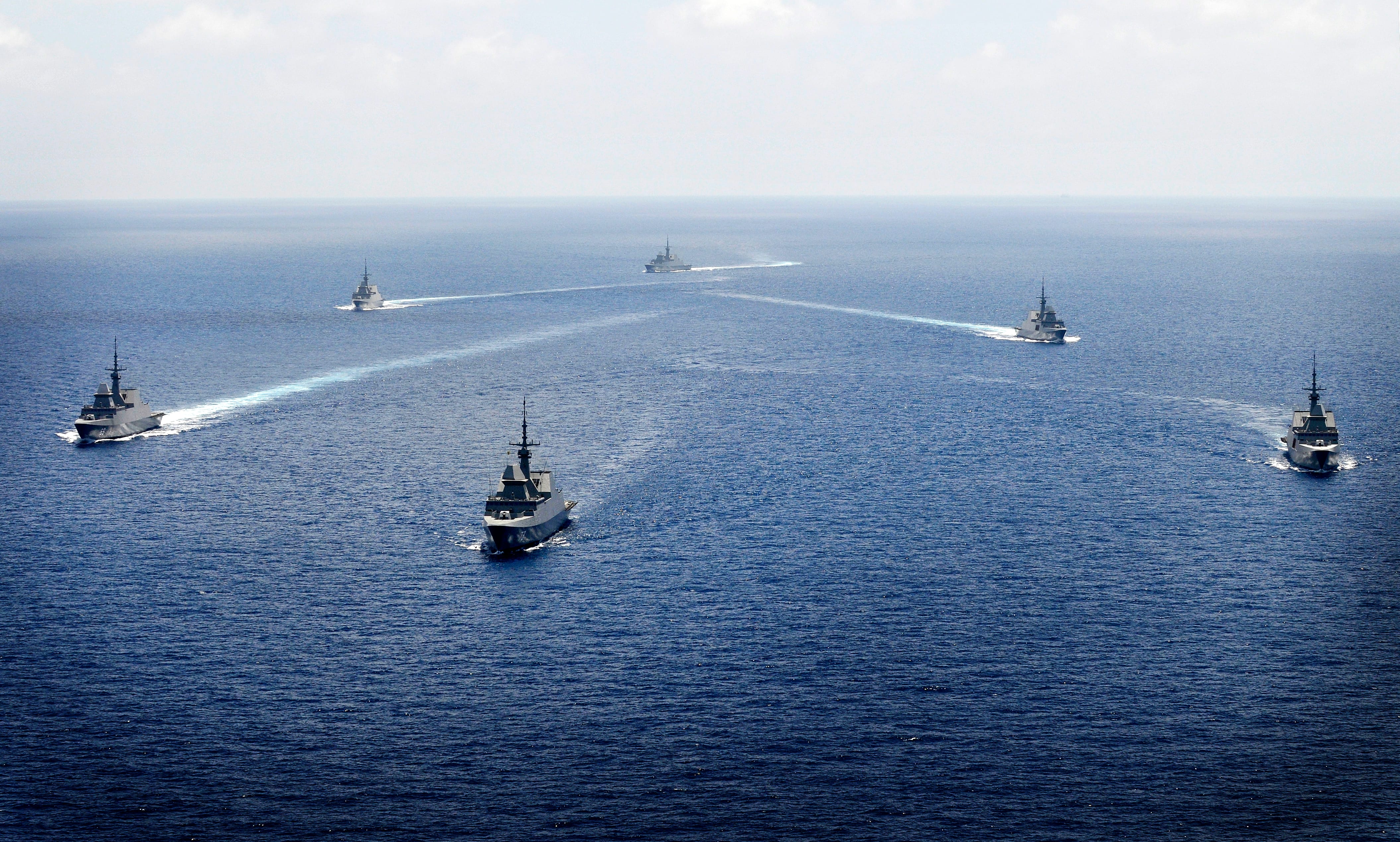 A formation of Singapore Navy warships sailing together in the open sea.
