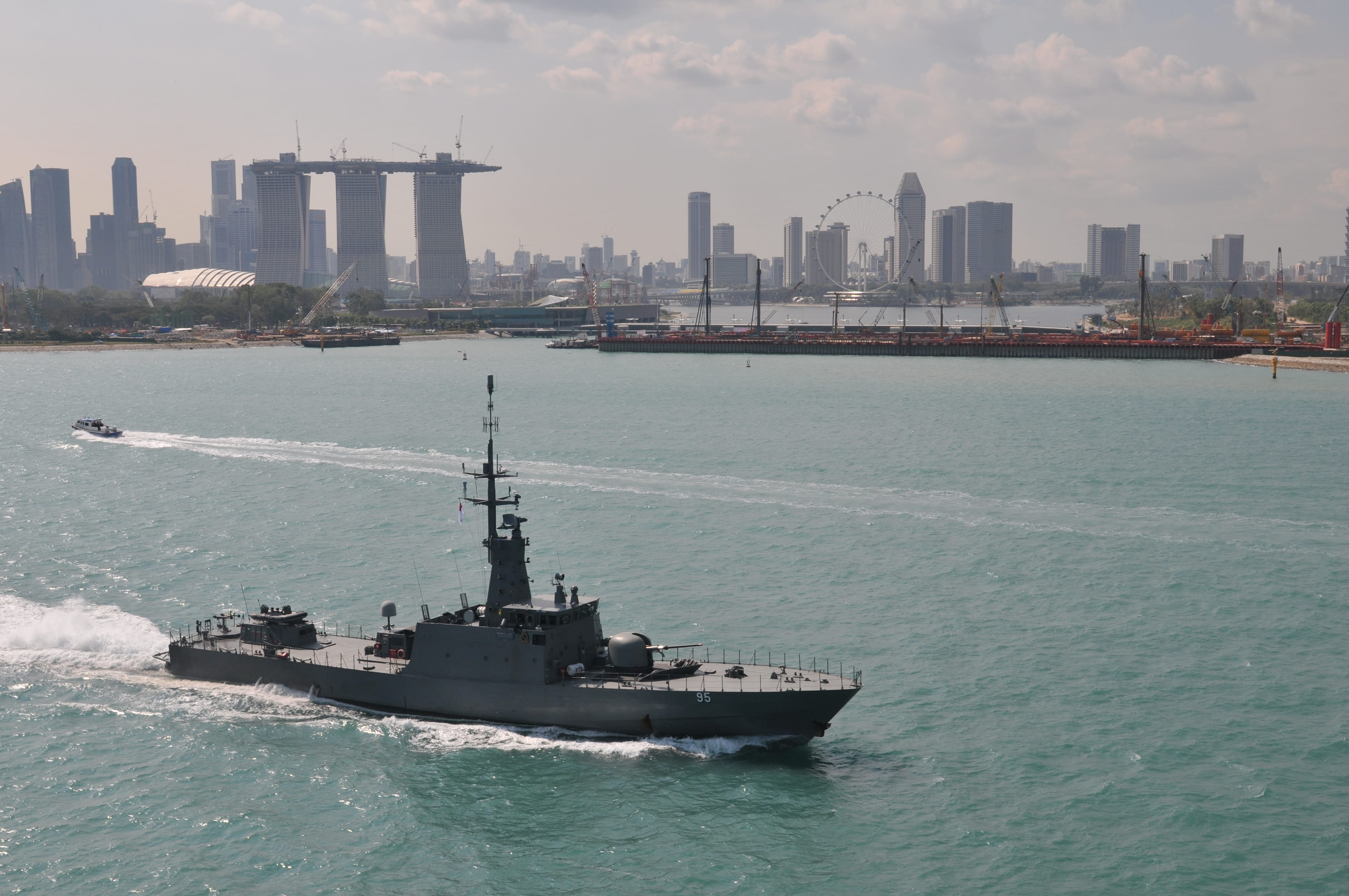 A patrol vessel sails near the Singapore skyline, with Marina Bay Sands and the Singapore Flyer in view.