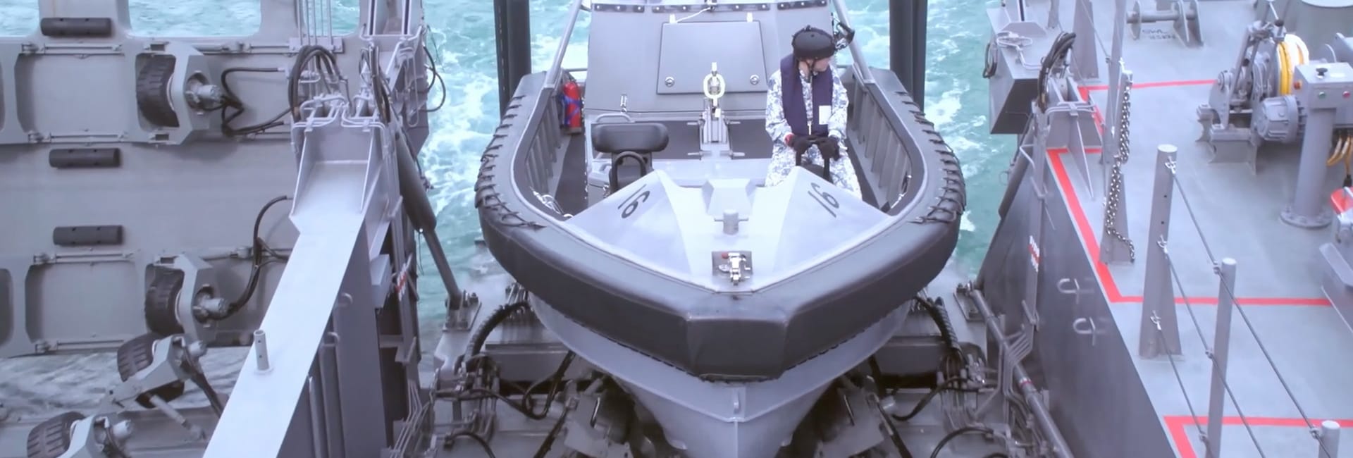 RHB on launcher ramp with uniformed crew seated inside, preparing for deployment.