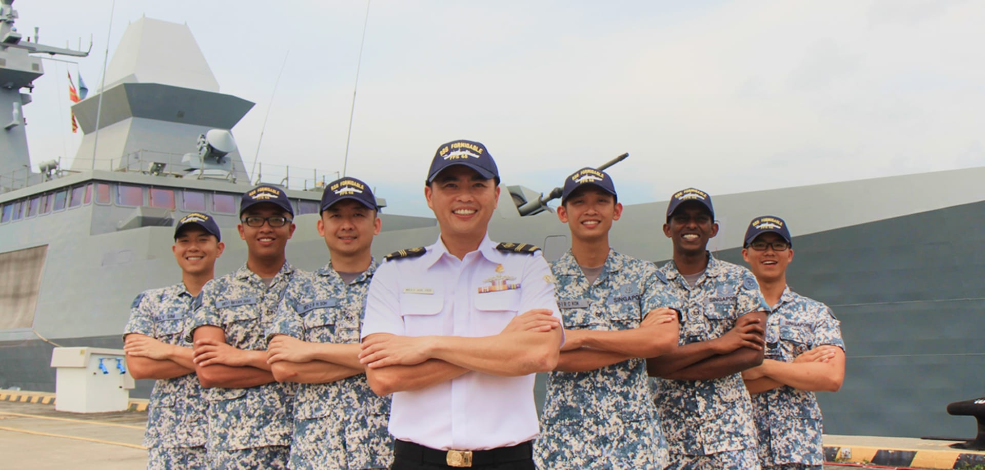 ME4 Joe and six sailors pose proudly in front of RSS Formidable at the naval base.