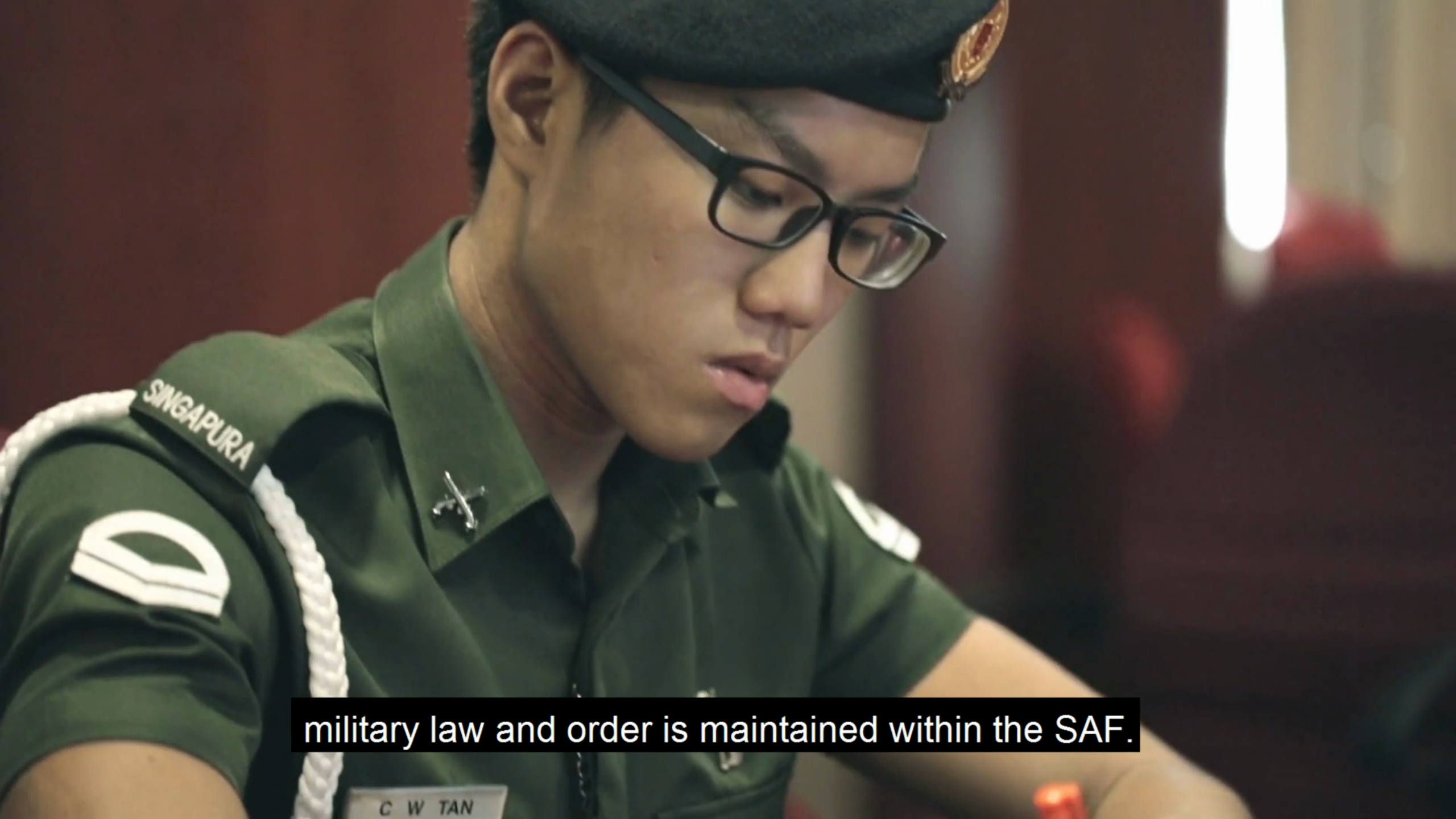 SAF Military Police personnel in green uniform writing during a briefing or administrative task.