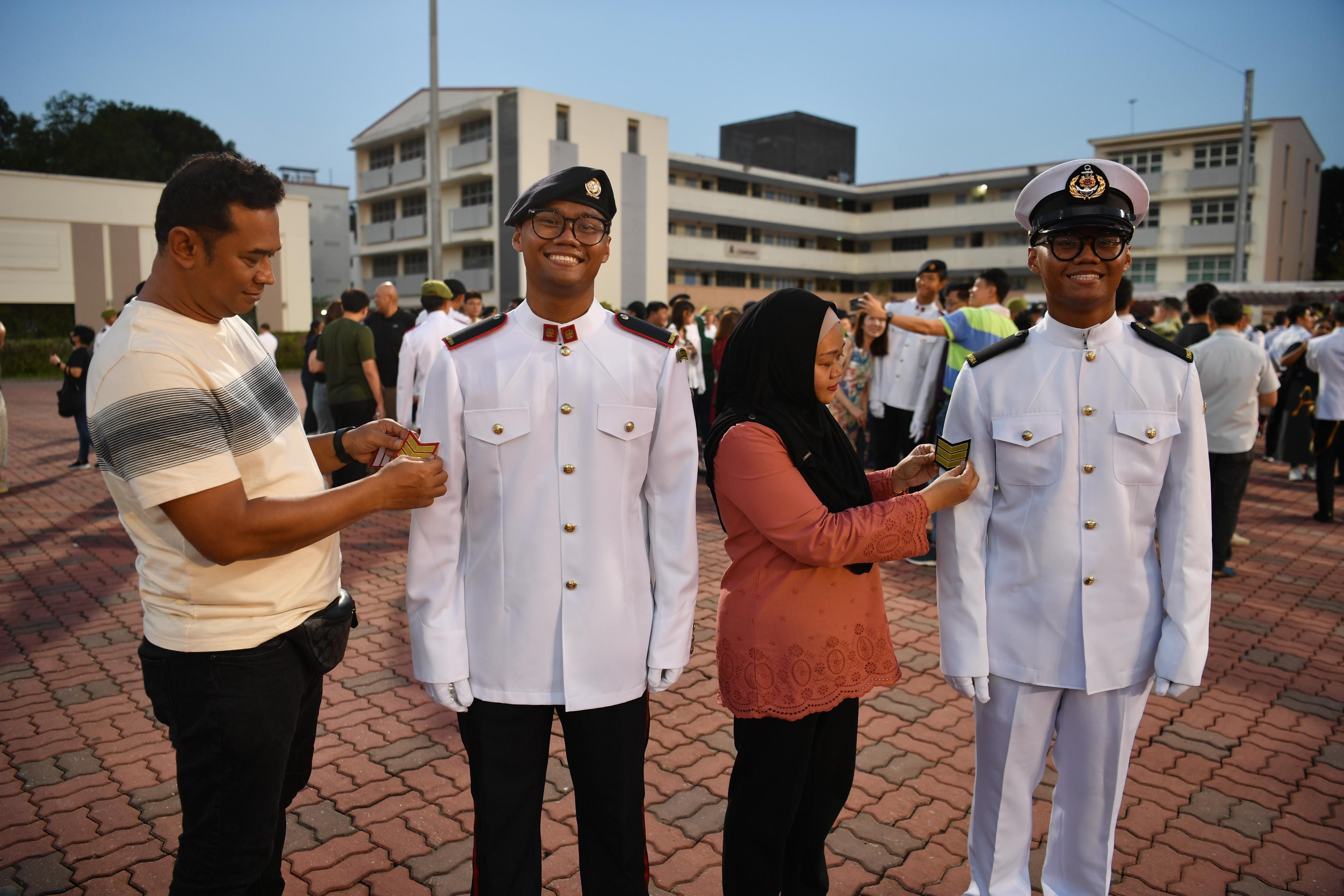 3SG Irfan Hidayat and 3SG Iryan Hidayat having their chevron ranks affixed by their family.