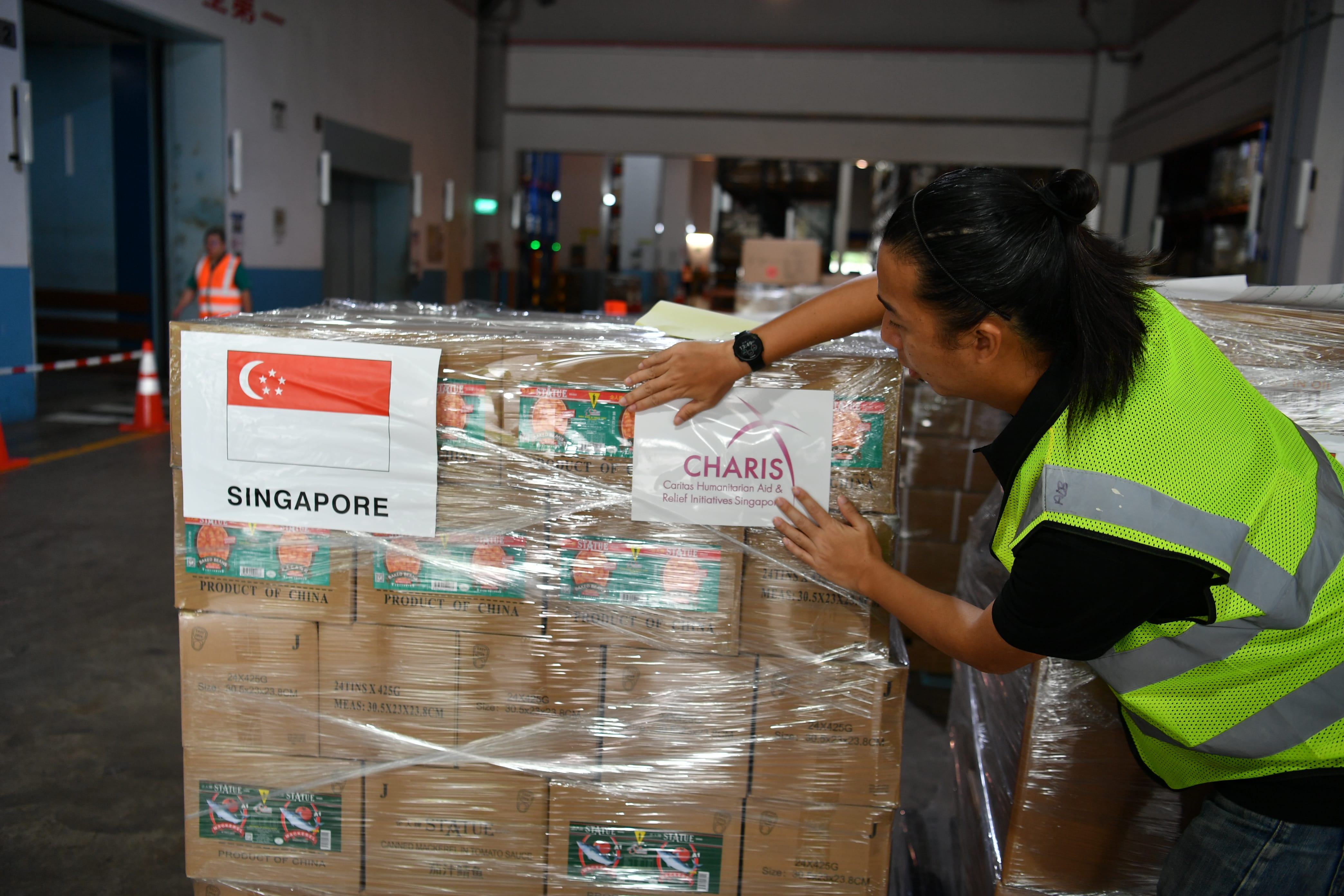 A Caritas Humanitarian Aid & Relief Initiatives Singapore (CHARIS) representative preparing a humanitarian aid pallet. 