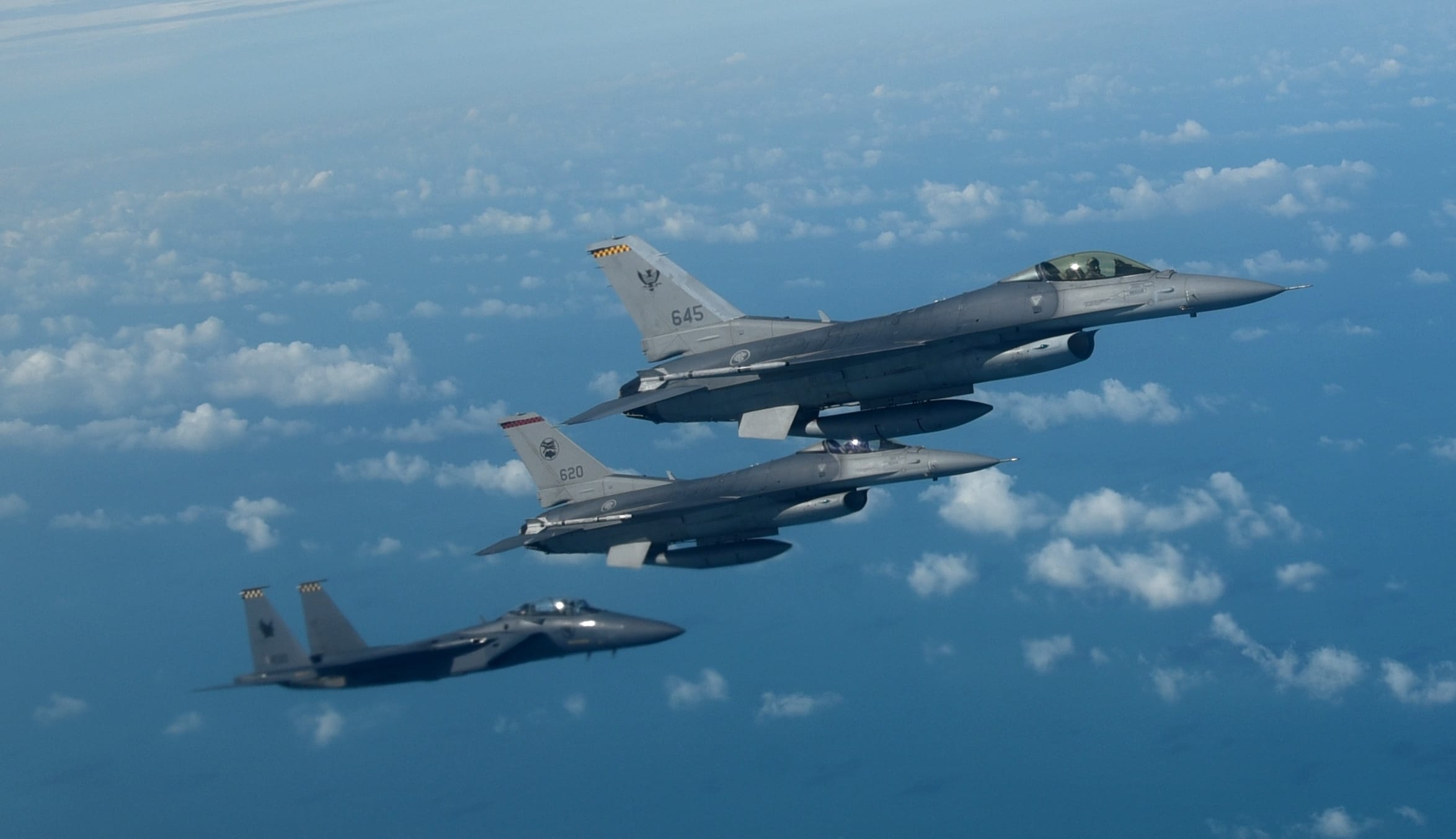 An RSAF F-15SG and two F-16s flying in close formation.