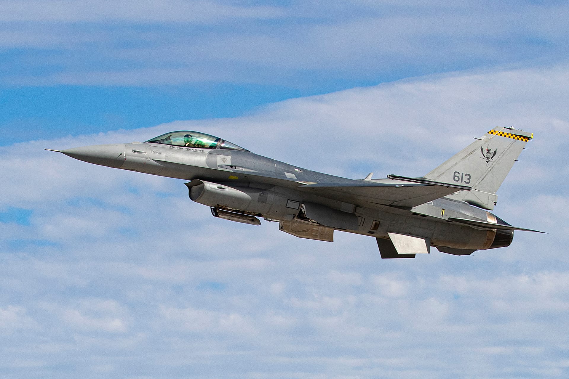 RSAF upgraded F-16 fighter jet in flight against a cloudy blue sky background.