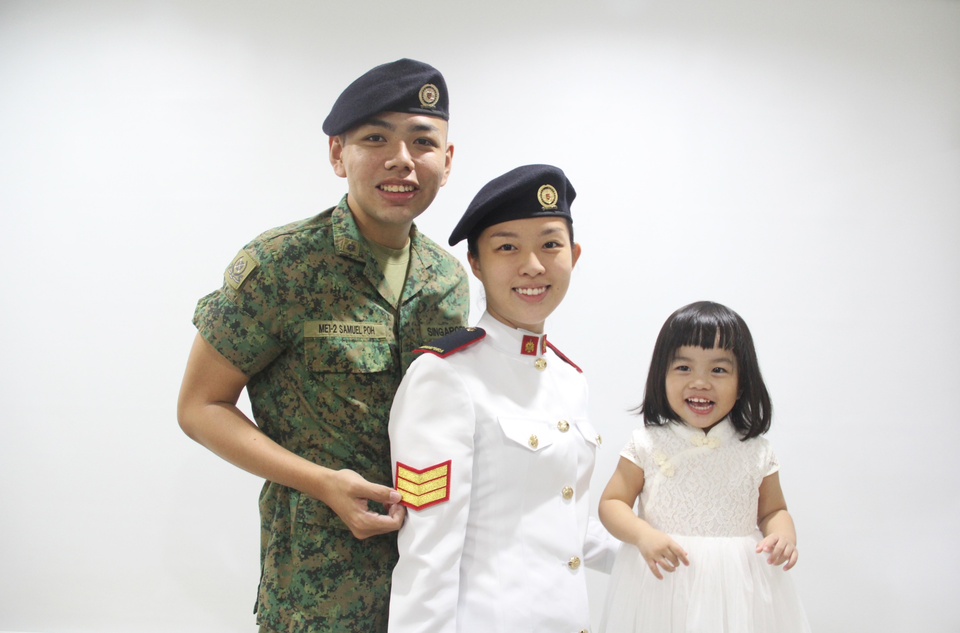3SG Kristin Poh (centre) having her rank affixed in the presence of her husband, Military Expert (ME) 1 Samuel Poh (left), and their daughter at home.