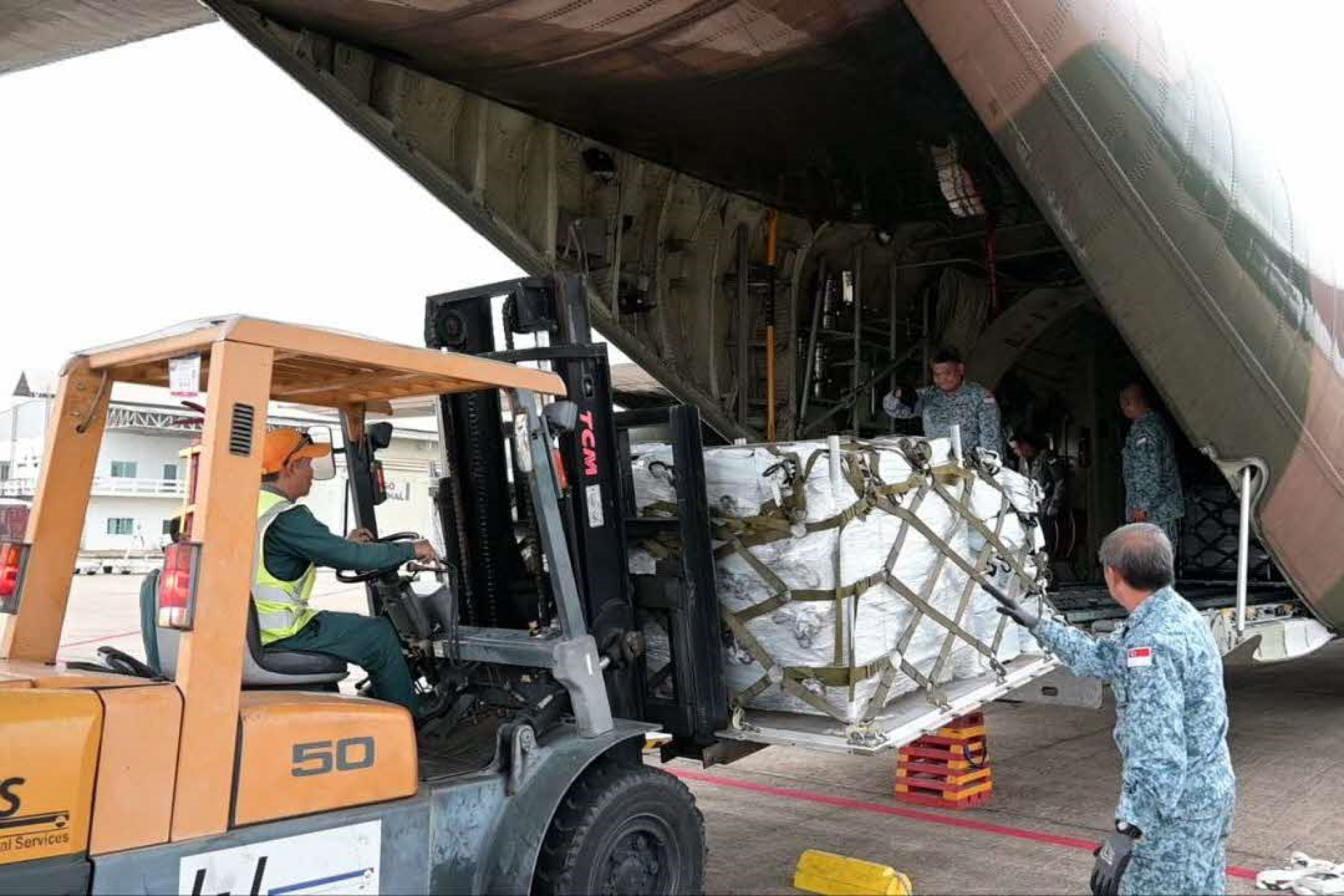 Personnel from the Republic of Singapore Air Force (RSAF) unloading the humanitarian aid supplies from the C-130 in Vientiane, Laos.