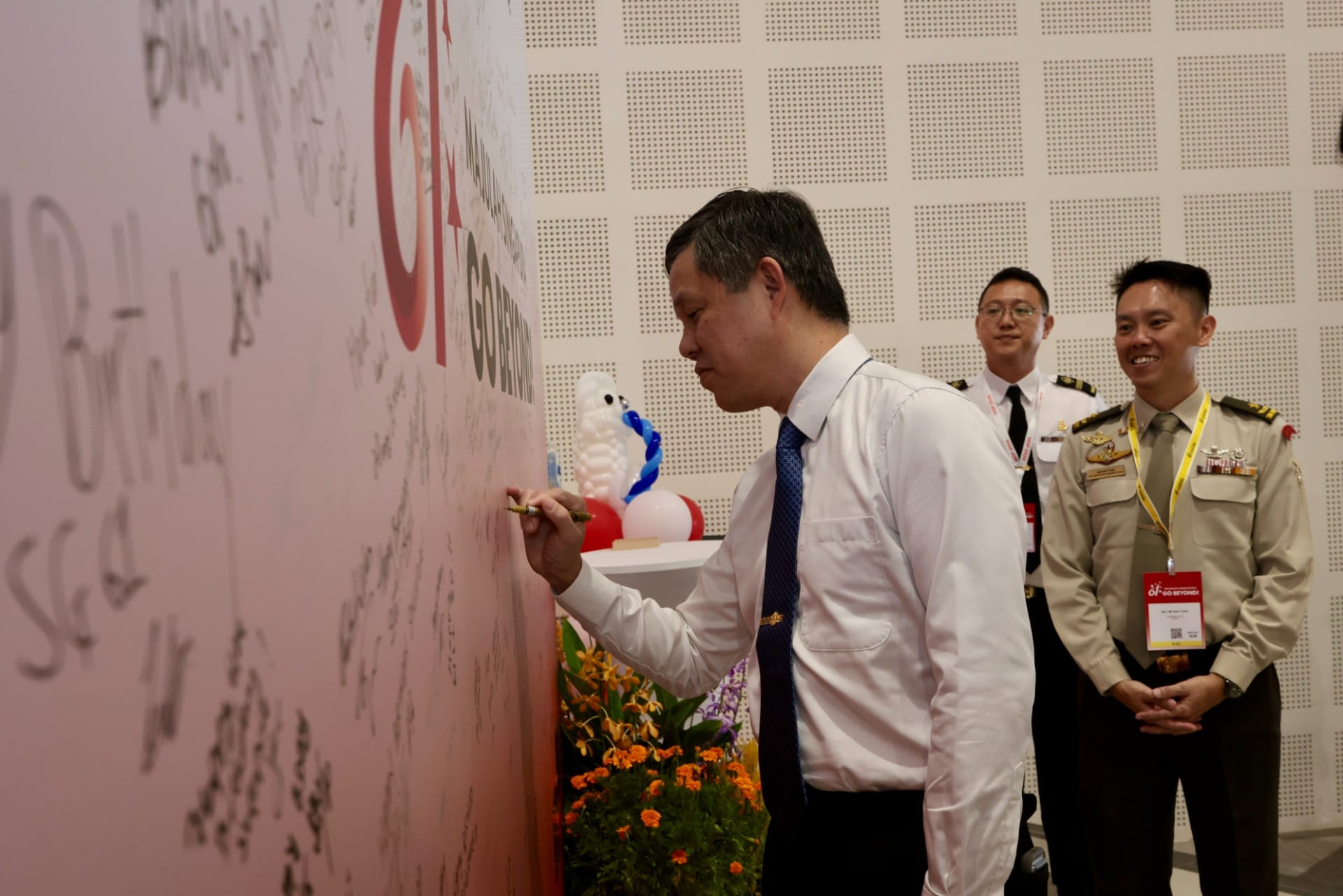 Minister Chan writing well wishes on the signature wall at the NDP 2026 Appreciation Function.